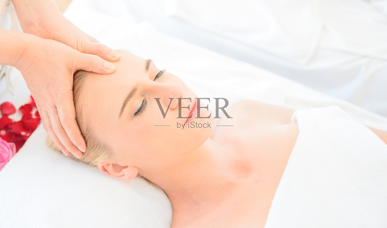 在水疗沙龙接受头部和面部按摩的美丽女人。身体保健的概念和传统泰式按摩放松照片摄影图片