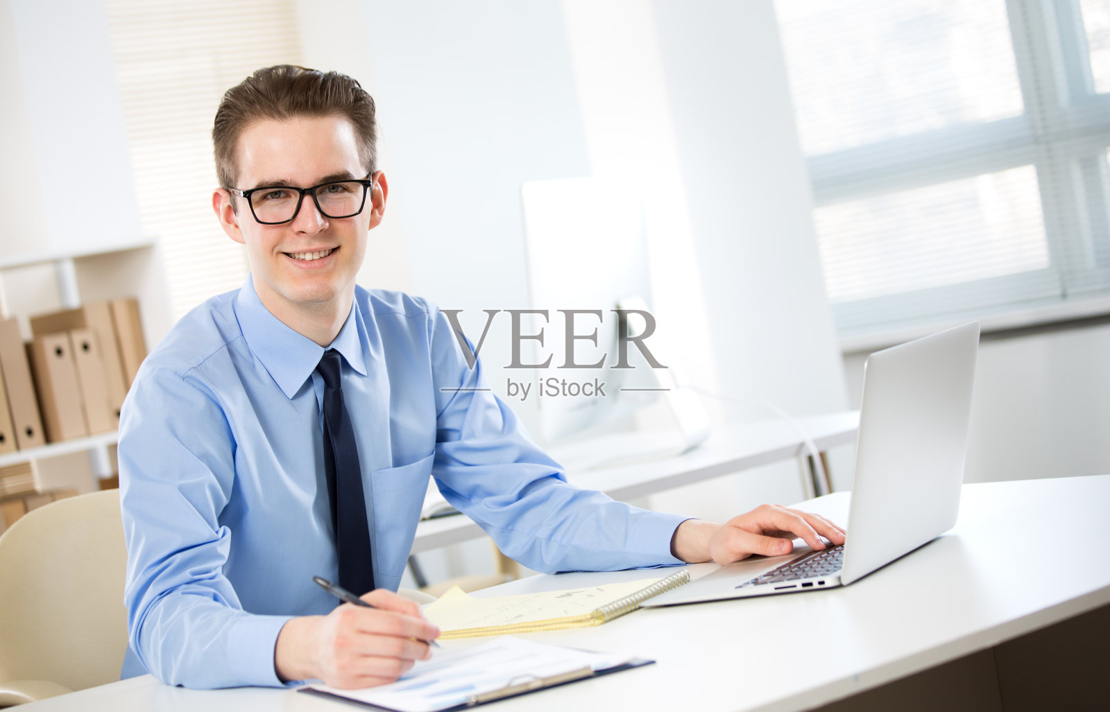 年轻商人在办公室用笔记本电脑工作的肖像照片摄影图片