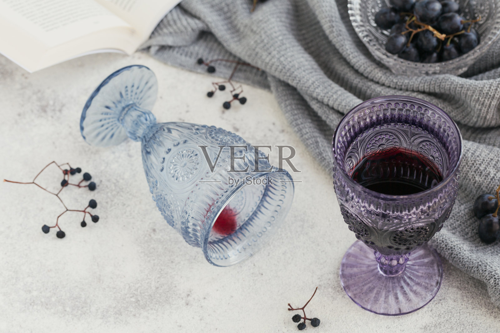 两杯红酒，一本书，黑葡萄和干浆果，在一个明亮的背景。秋天情绪的概念。照片摄影图片