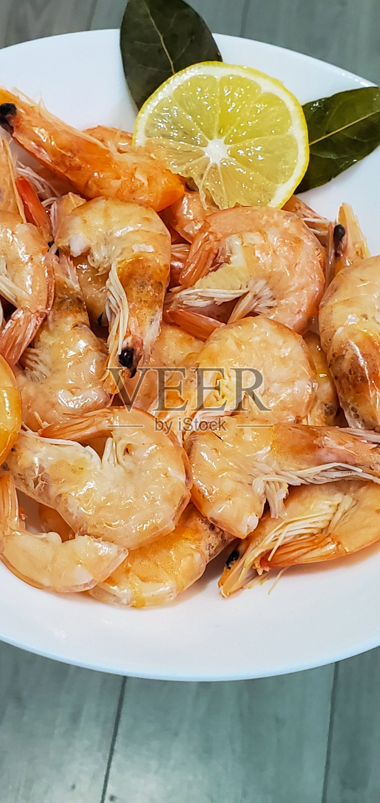 白盘子里的虾和柠檬。海鲜。盘子上的虾，孤立在灰色背景上照片摄影图片