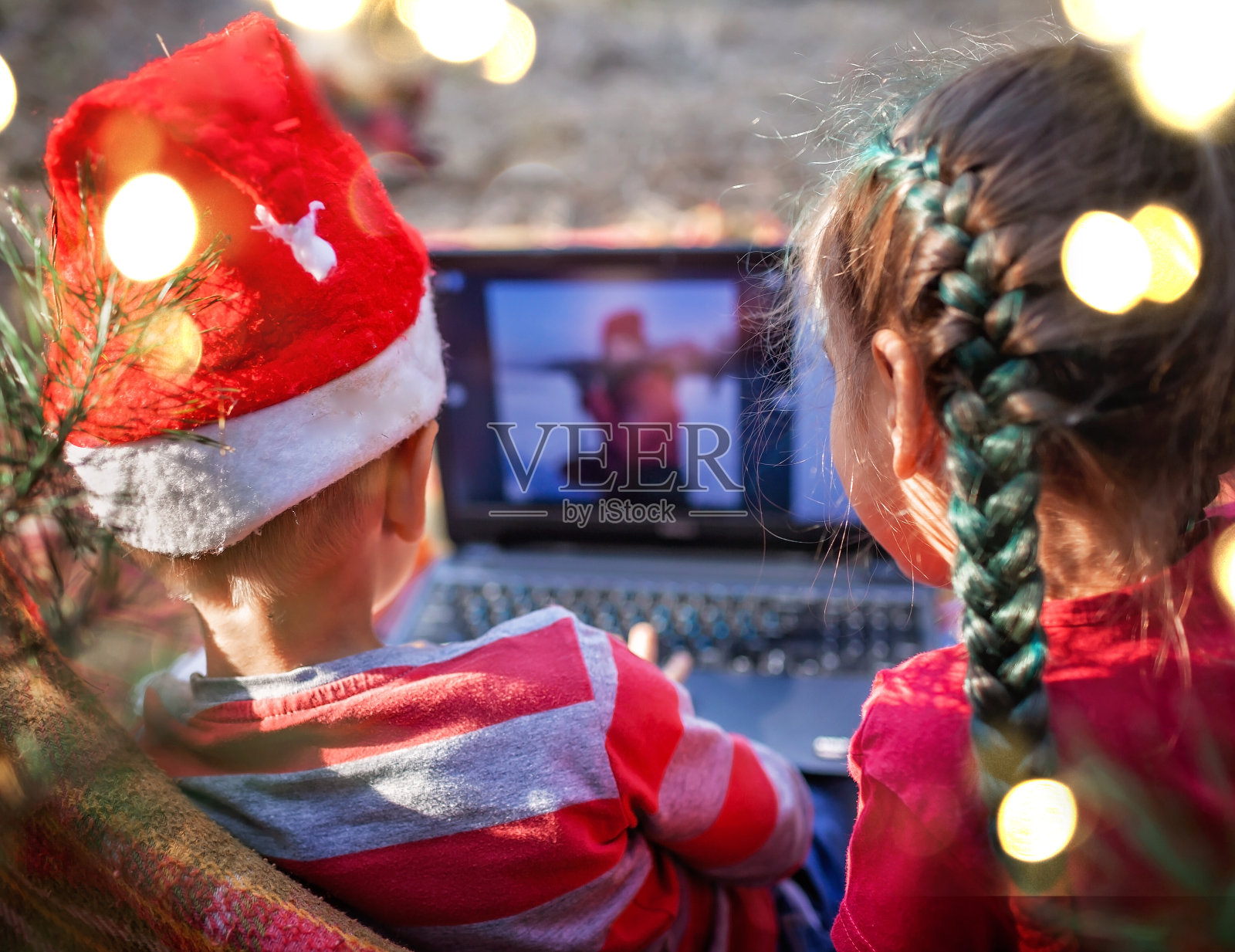 新常态的网上圣诞庆祝活动。孩子们通过视频聊天与家人庆祝照片摄影图片