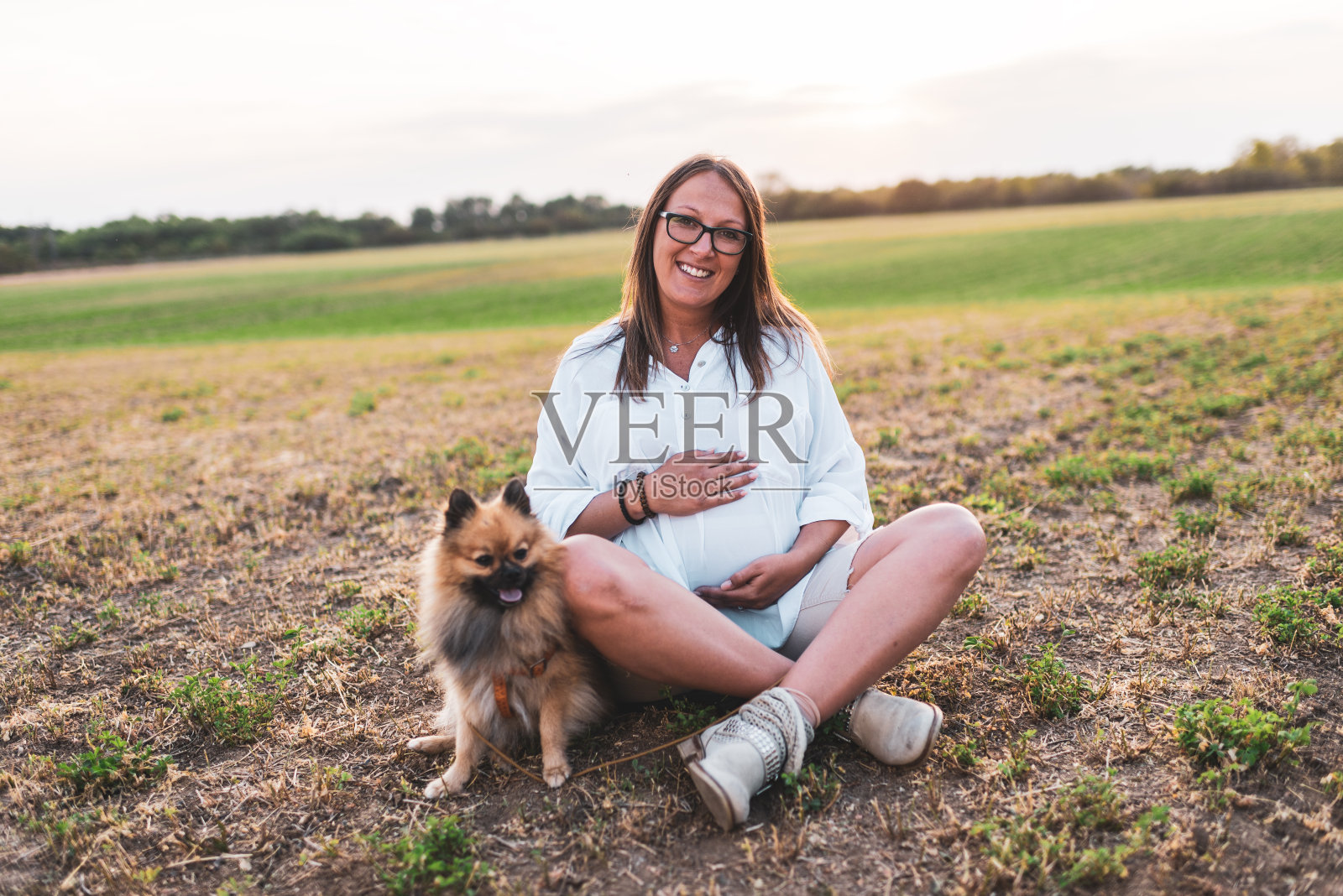 一个年轻孕妇在户外和狗玩耍照片摄影图片