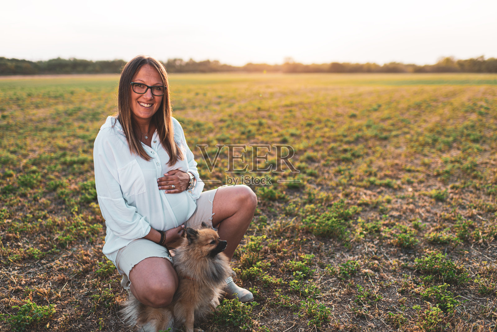 一个孕妇在户外和一只狗玩耍的肖像照片摄影图片