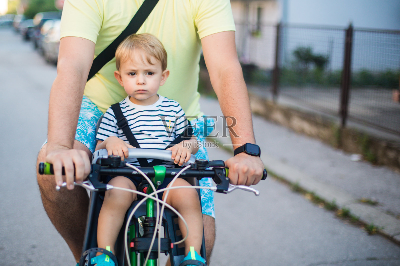 父亲骑着自行车，儿子坐在座位上照片摄影图片