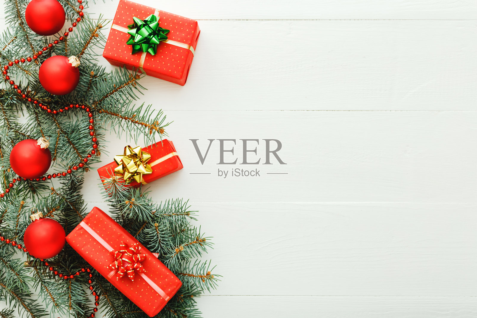 2020年圣诞新年庆祝模式组成的红色礼品盒，杉木树枝，球在白色的木制背景。概念圣诞时间，冬天。平铺，俯视图，拷贝空间照片摄影图片