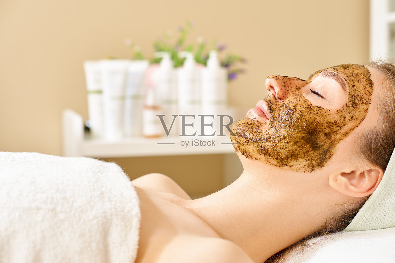 美丽的脸。肖像迷人的年轻女子把磨砂面部皮肤。特写美丽的女性去角质和擦洗皮肤照片摄影图片