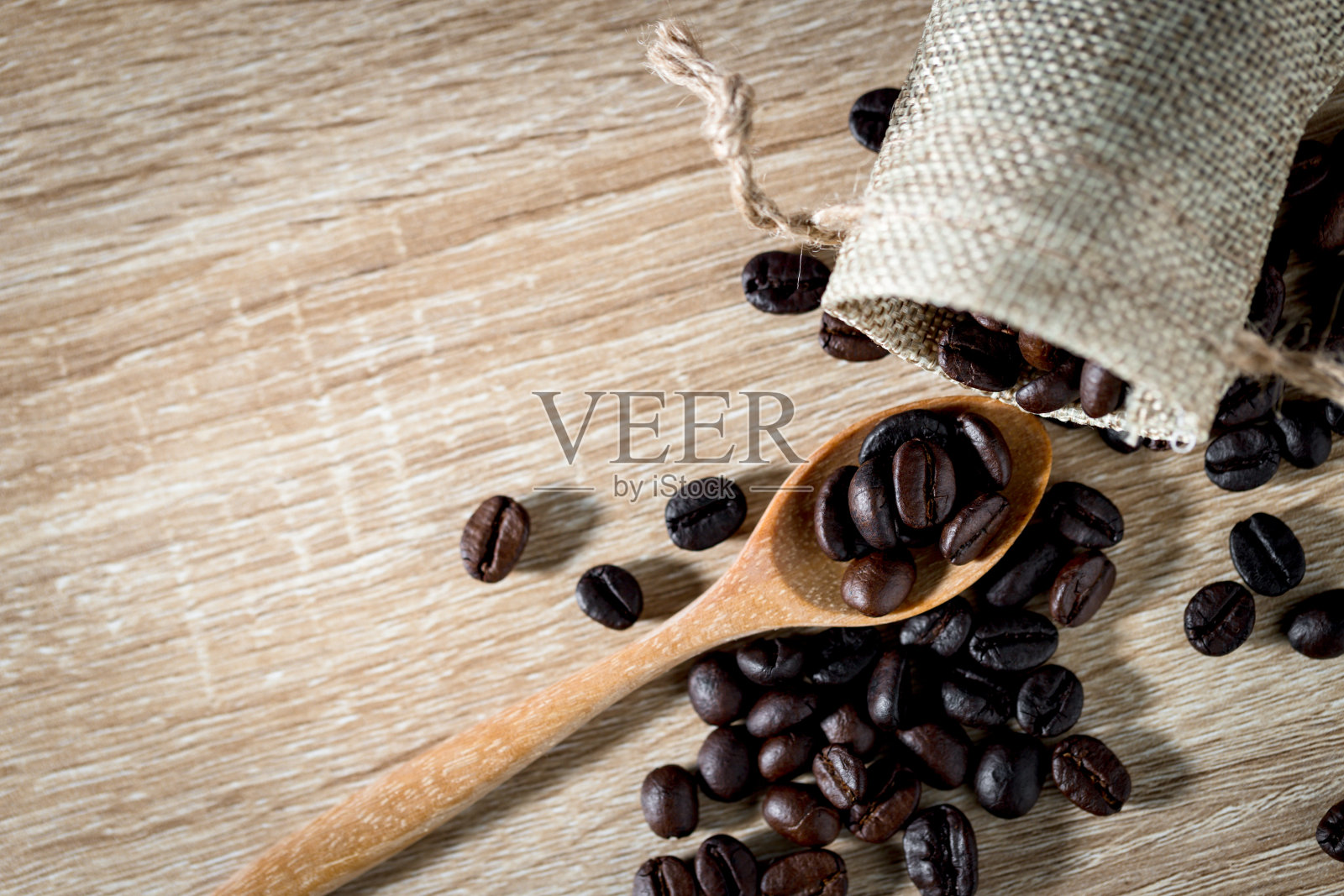 木桌背景是木勺上的咖啡豆。带有copyspace的俯视图照片摄影图片