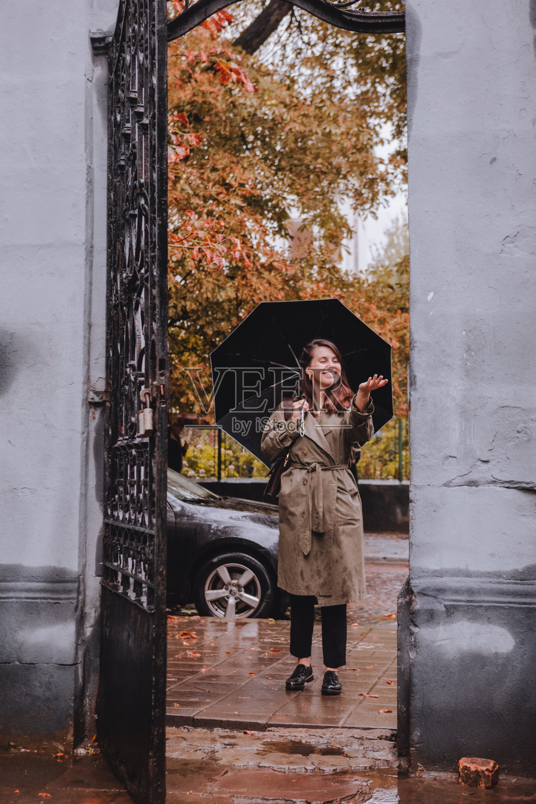 年轻漂亮的女人穿着秋装，在雨天撑着伞走在城市街道上照片摄影图片