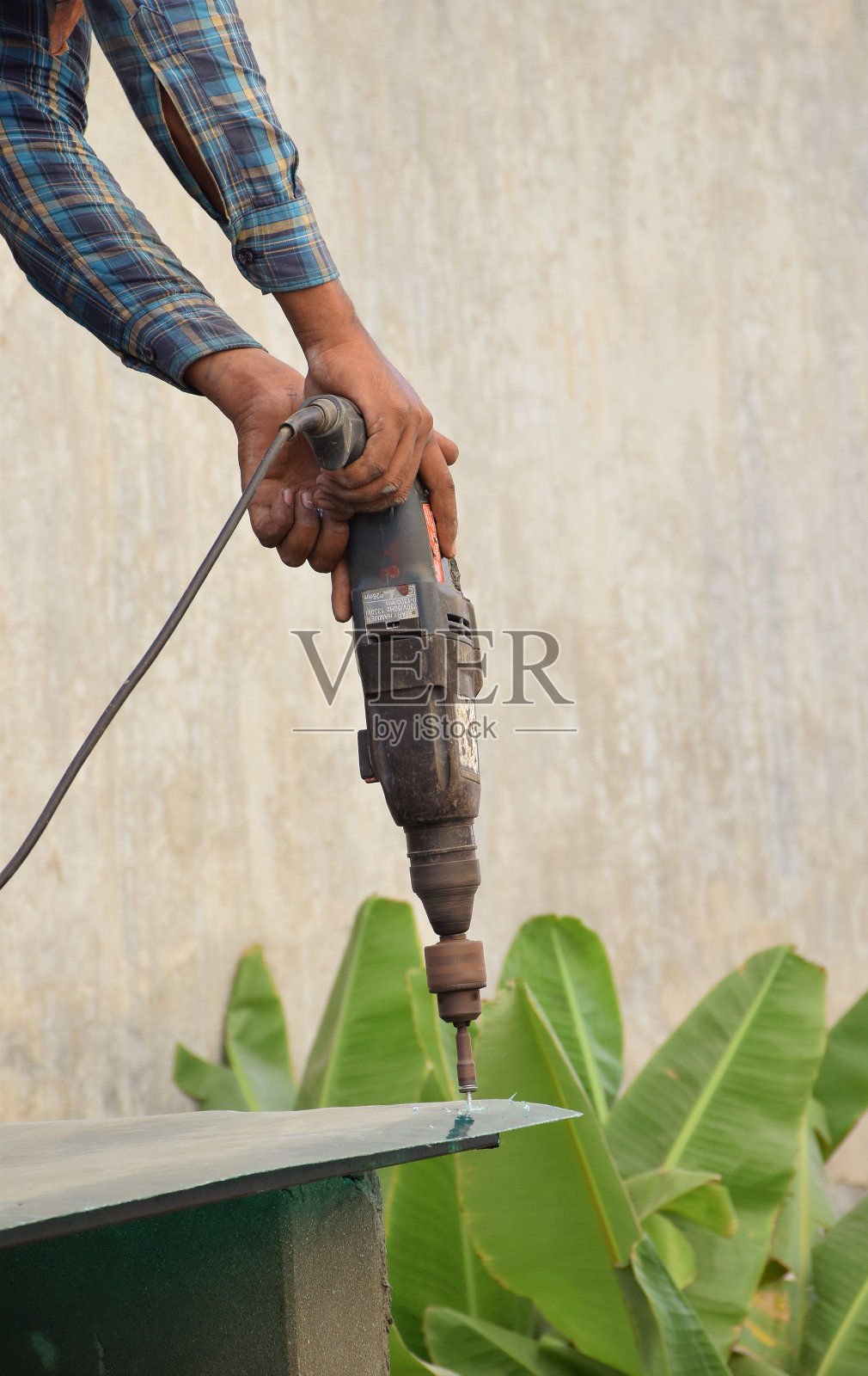 一名印度工人正在用钻机拧紧塑料片上的螺栓照片摄影图片