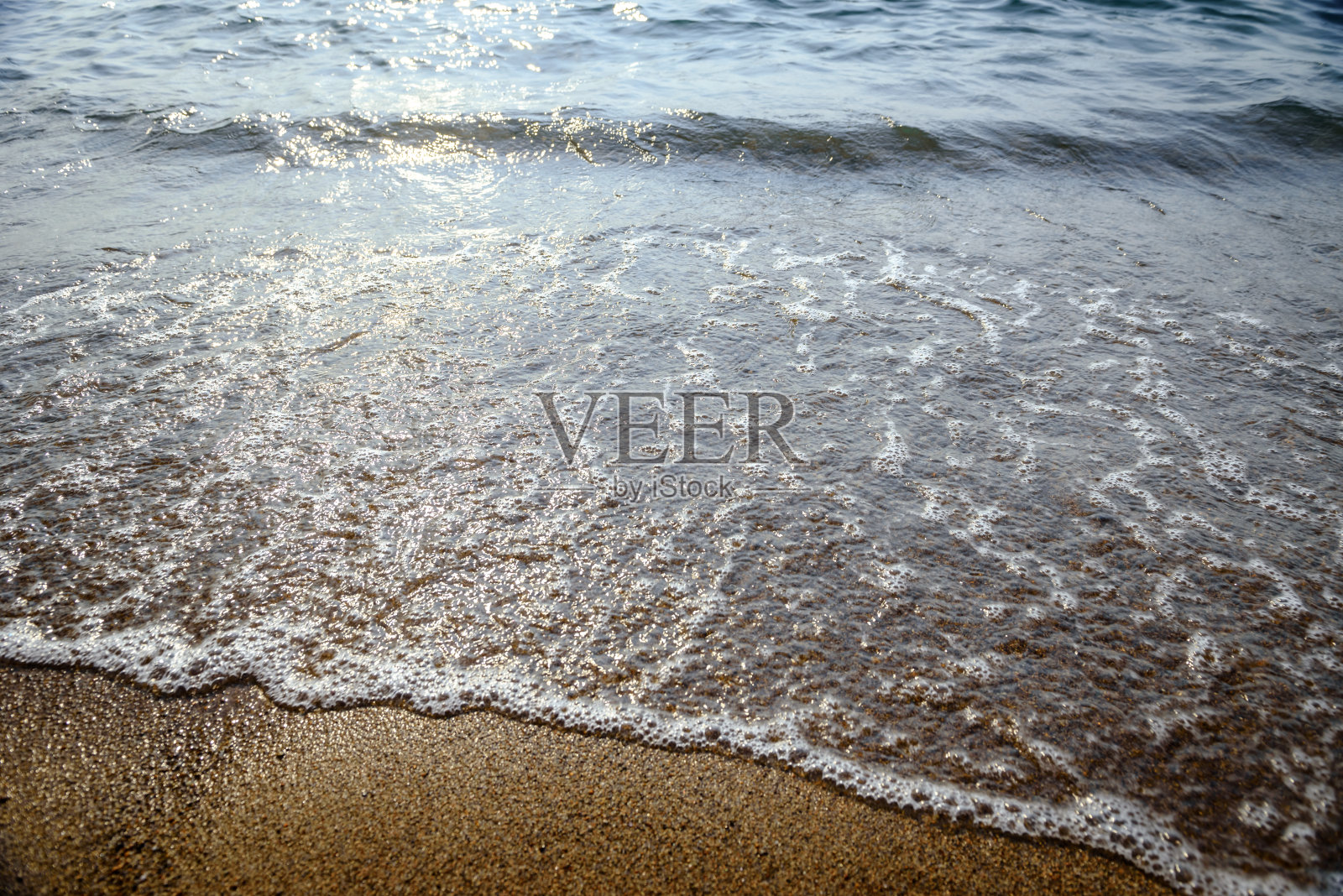 泡沫在沙滩上荡漾。照片摄影图片