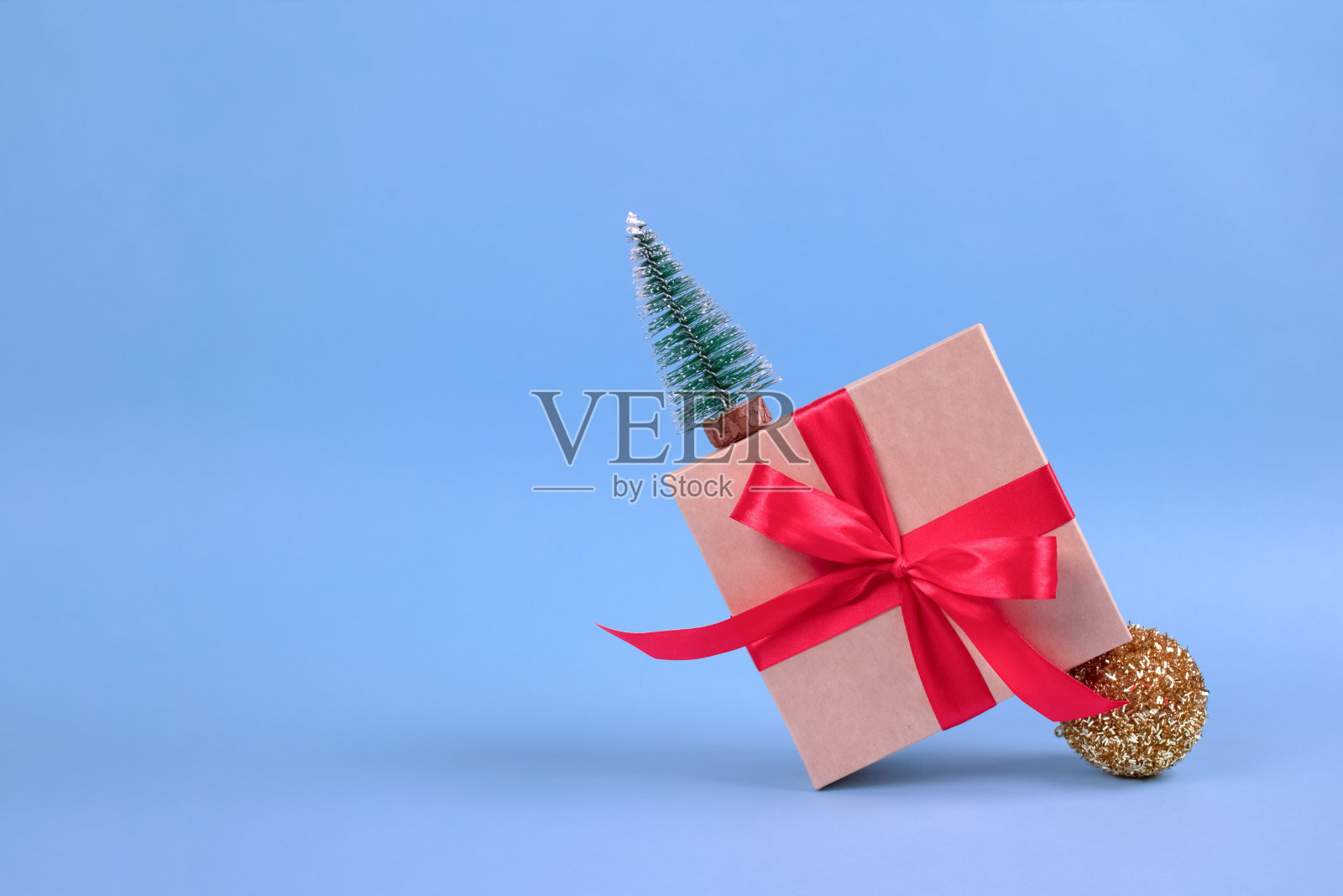 横幅与礼品盒与红色蝴蝶结和圣诞树装饰在节日蓝色背景与模糊散焦和copyspace为您的文本。圣诞节或新年庆祝概念照片摄影图片