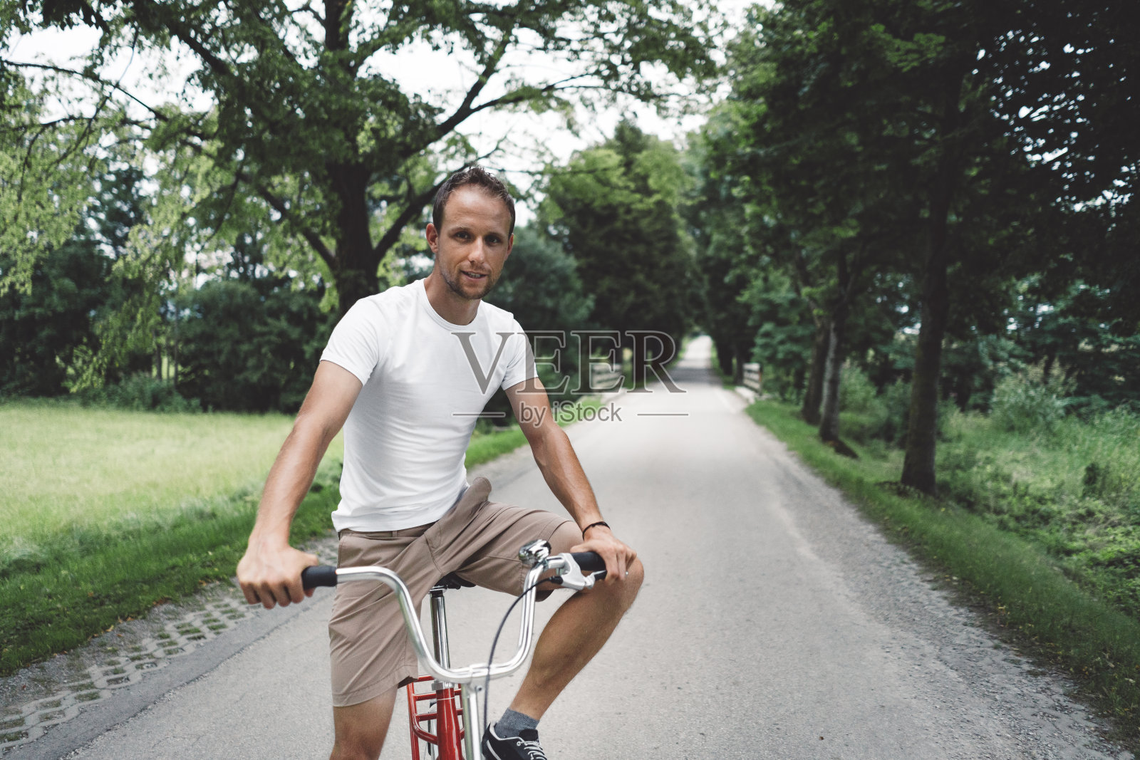 一个骑着红色自行车的快乐的人照片摄影图片