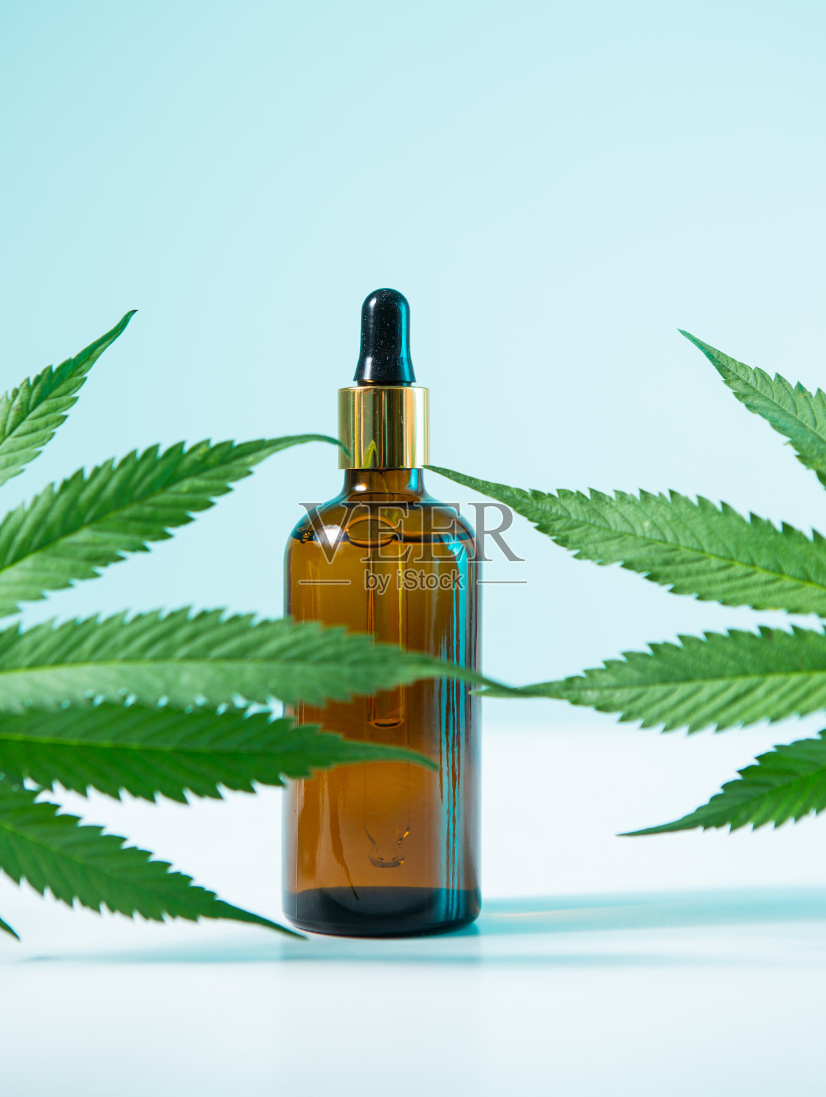 玻璃罐与CBD产品和大麻叶在霓虹灯蓝色，近距离照片摄影图片