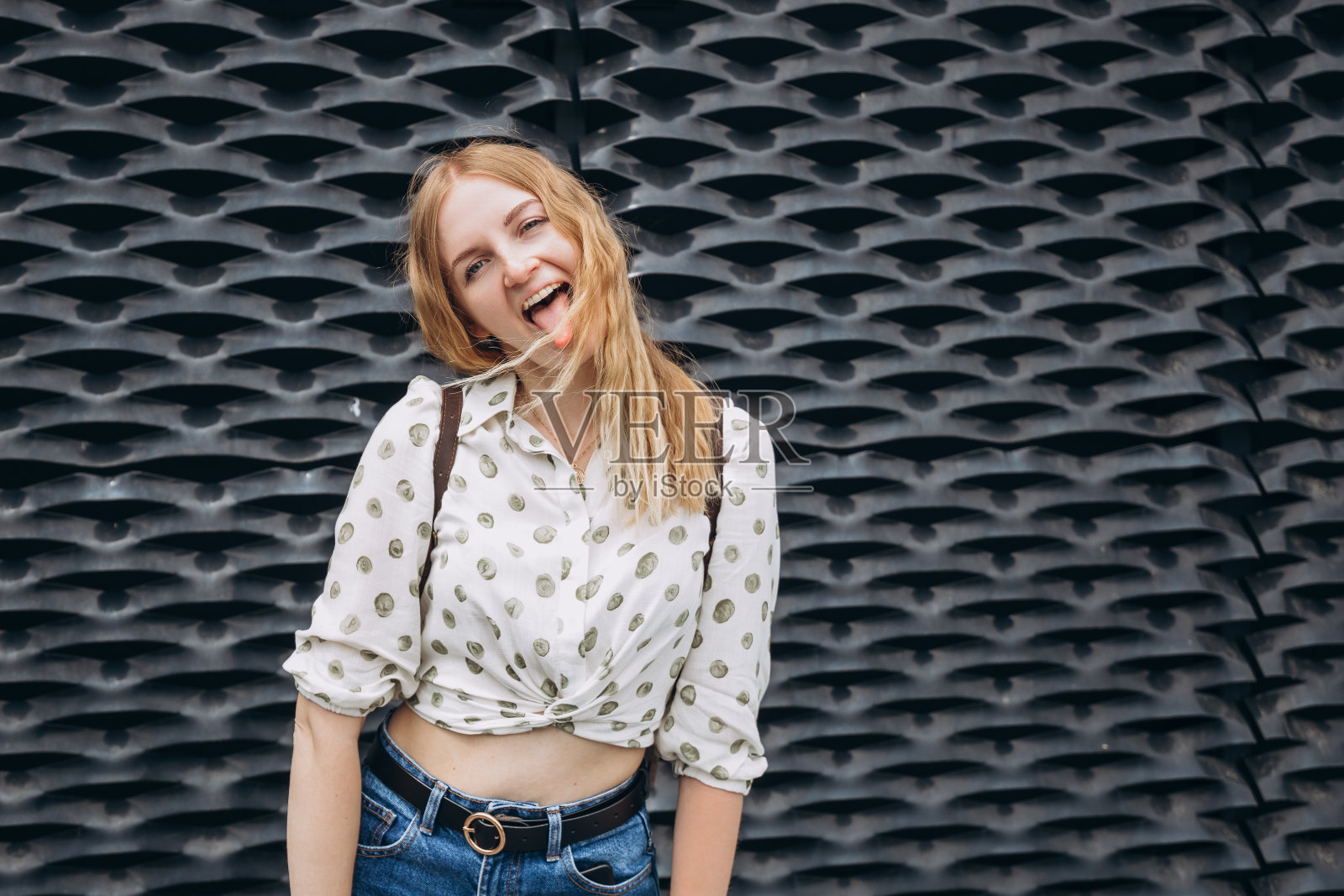 一个兴奋尖叫的年轻女子站在黑暗的背景下。照片摄影图片