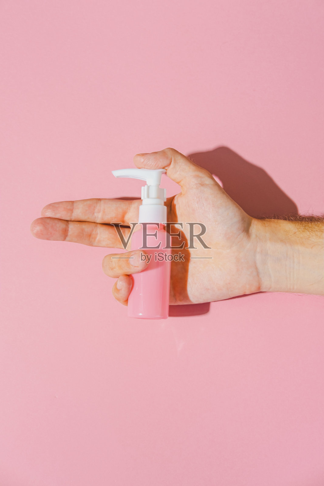 化妆品面霜空白瓶在手。粉红色背景上的有机生物产品。简约美和水疗单色枪射击概念。照片摄影图片