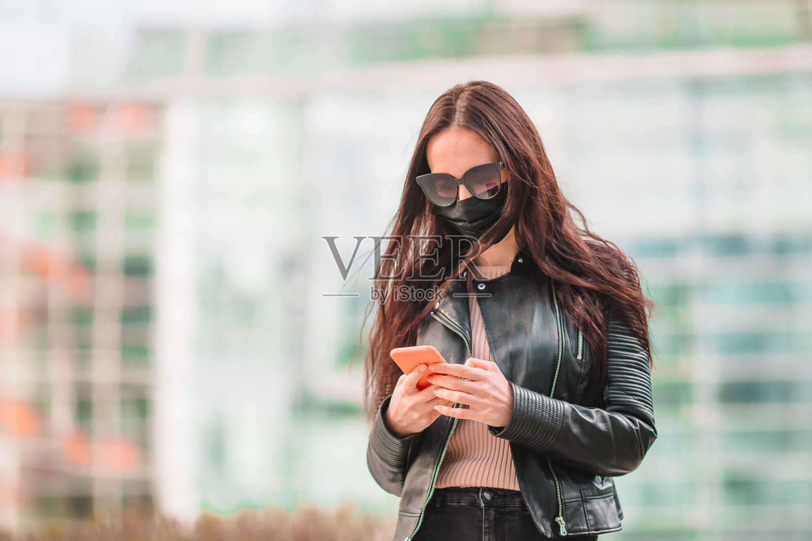 一个戴着面具的女人站在一座现代建筑的背景上，照片摄影图片