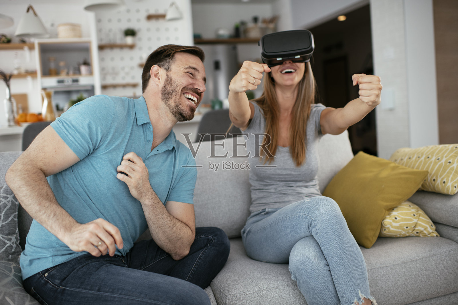 微笑的年轻女子使用虚拟现实头盔在家沙发上照片摄影图片