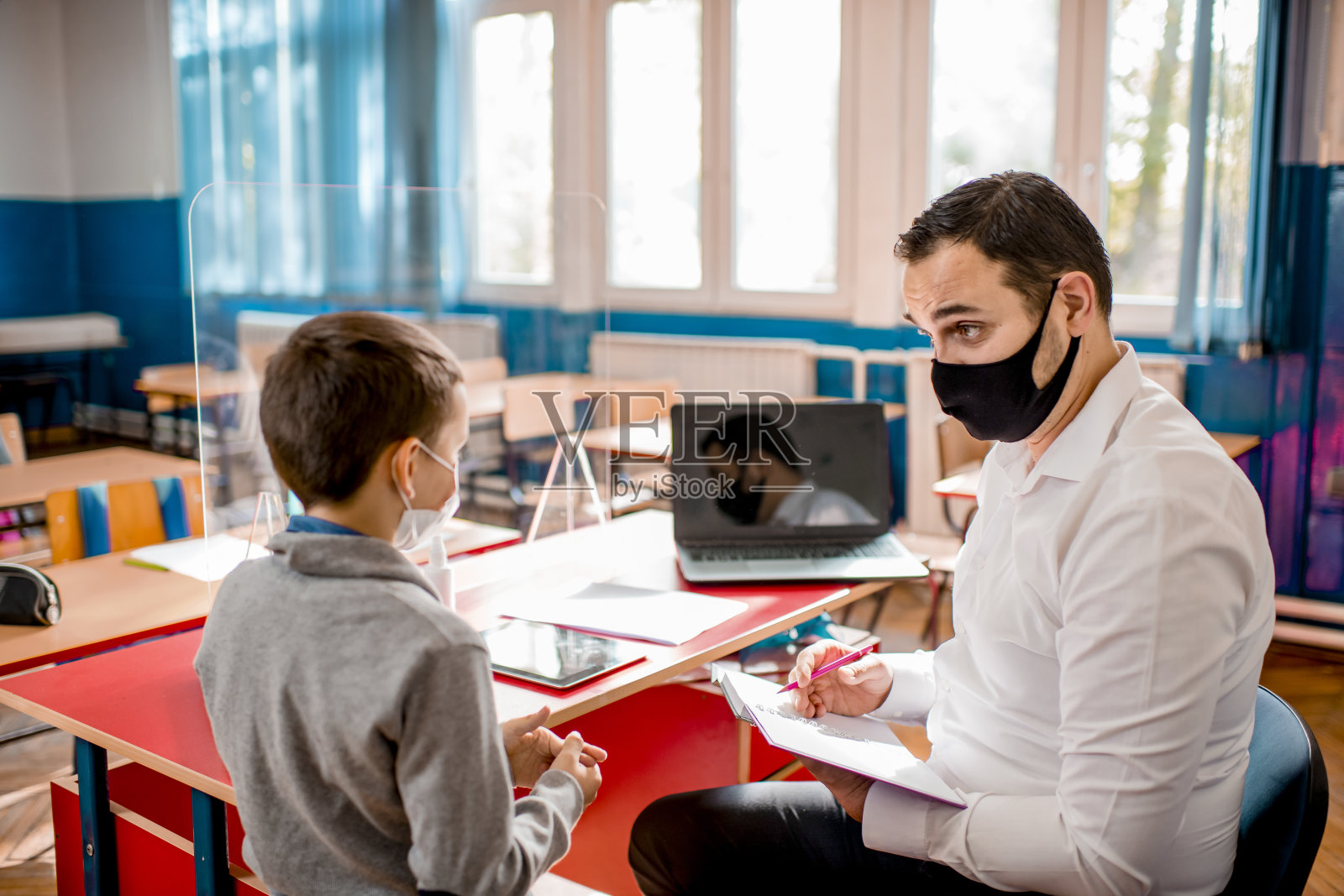小学生在教室里戴着防护口罩。教育在流行。照片摄影图片