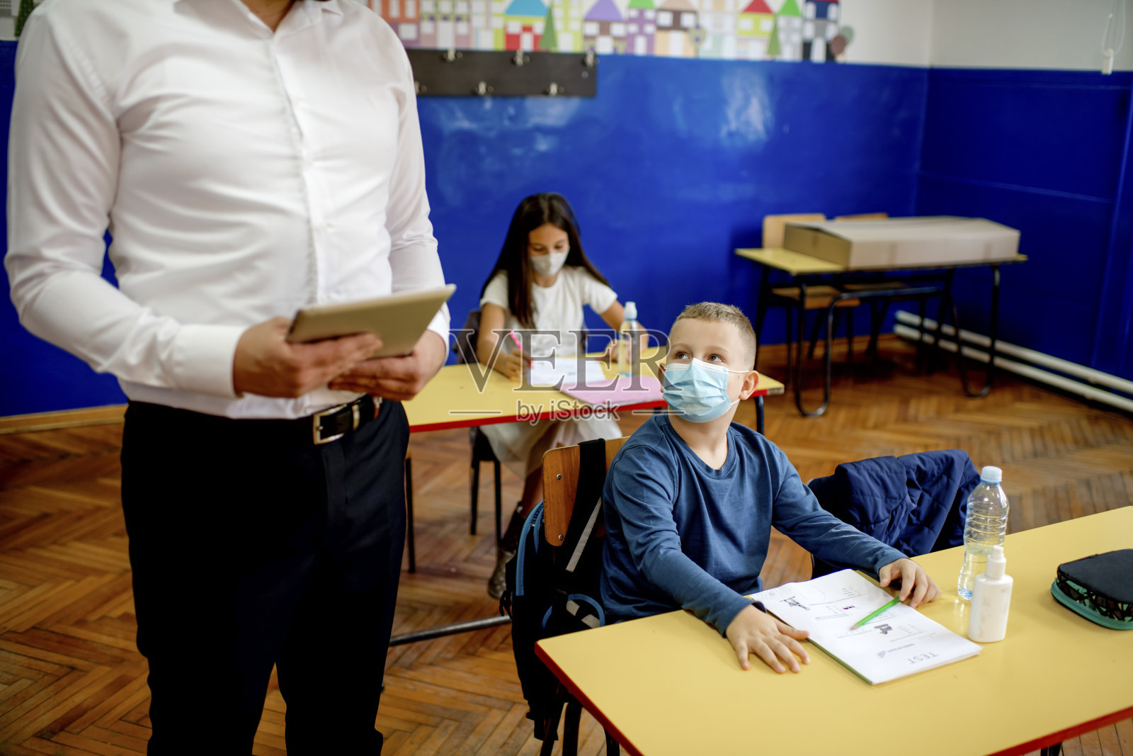小学生在教室里戴着防护口罩。教育在流行。照片摄影图片