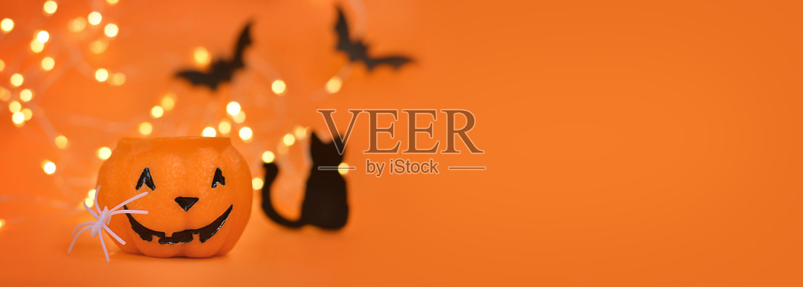 万圣节快乐!南瓜，蝙蝠，猫，蜘蛛在一个橙色的背景和一个发光的散焦背景。横幅，文本复制空间照片摄影图片