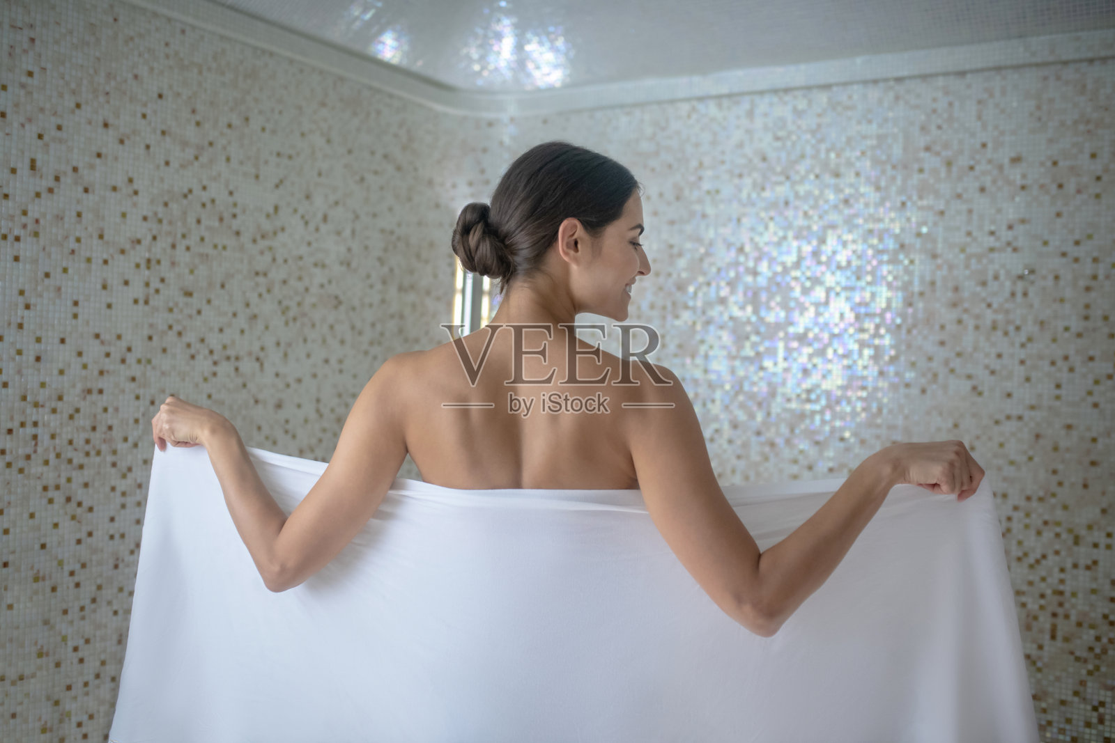 后视图黑头发的女性包裹自己在白色的毛巾照片摄影图片