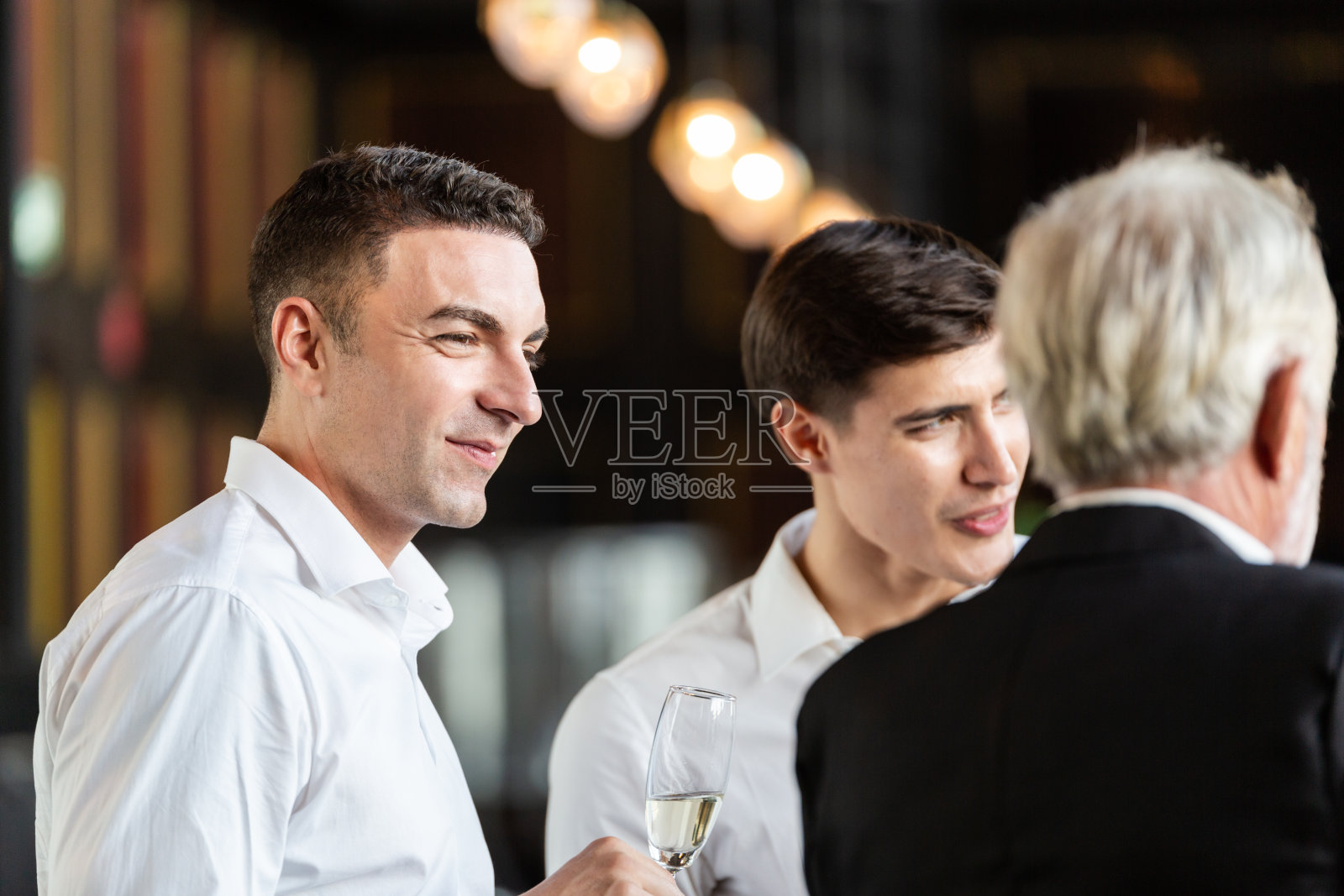 拿着酒杯与同事交谈的商人。办公室员工开研讨会派对。公司公司会议在新年庆祝概念照片摄影图片