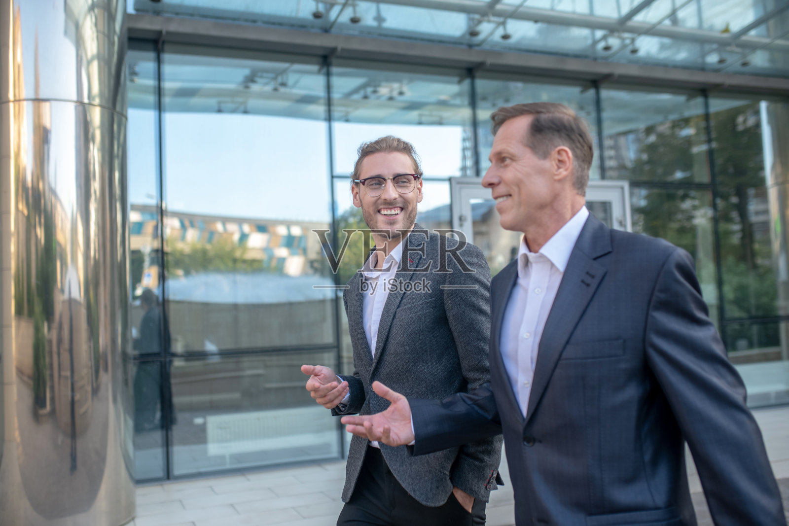 两个微笑着的商业伙伴走在外面，友好地交谈着照片摄影图片