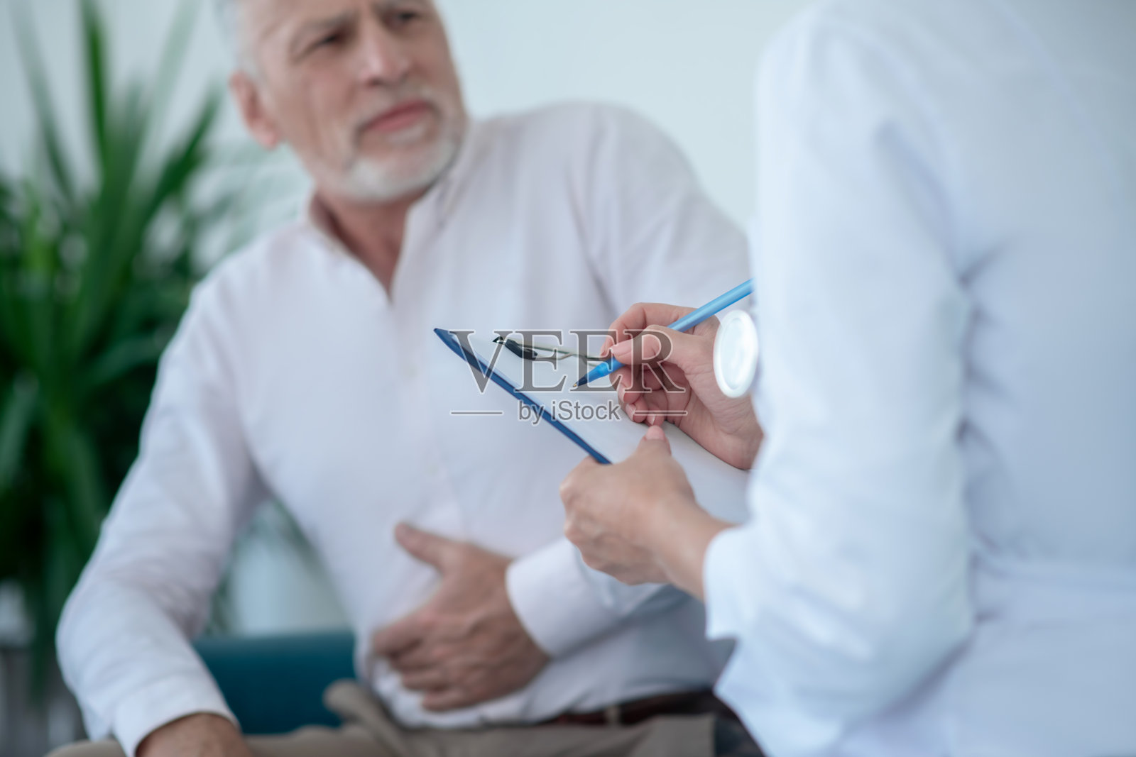 白发男病人胃痛，女医生开处方照片摄影图片