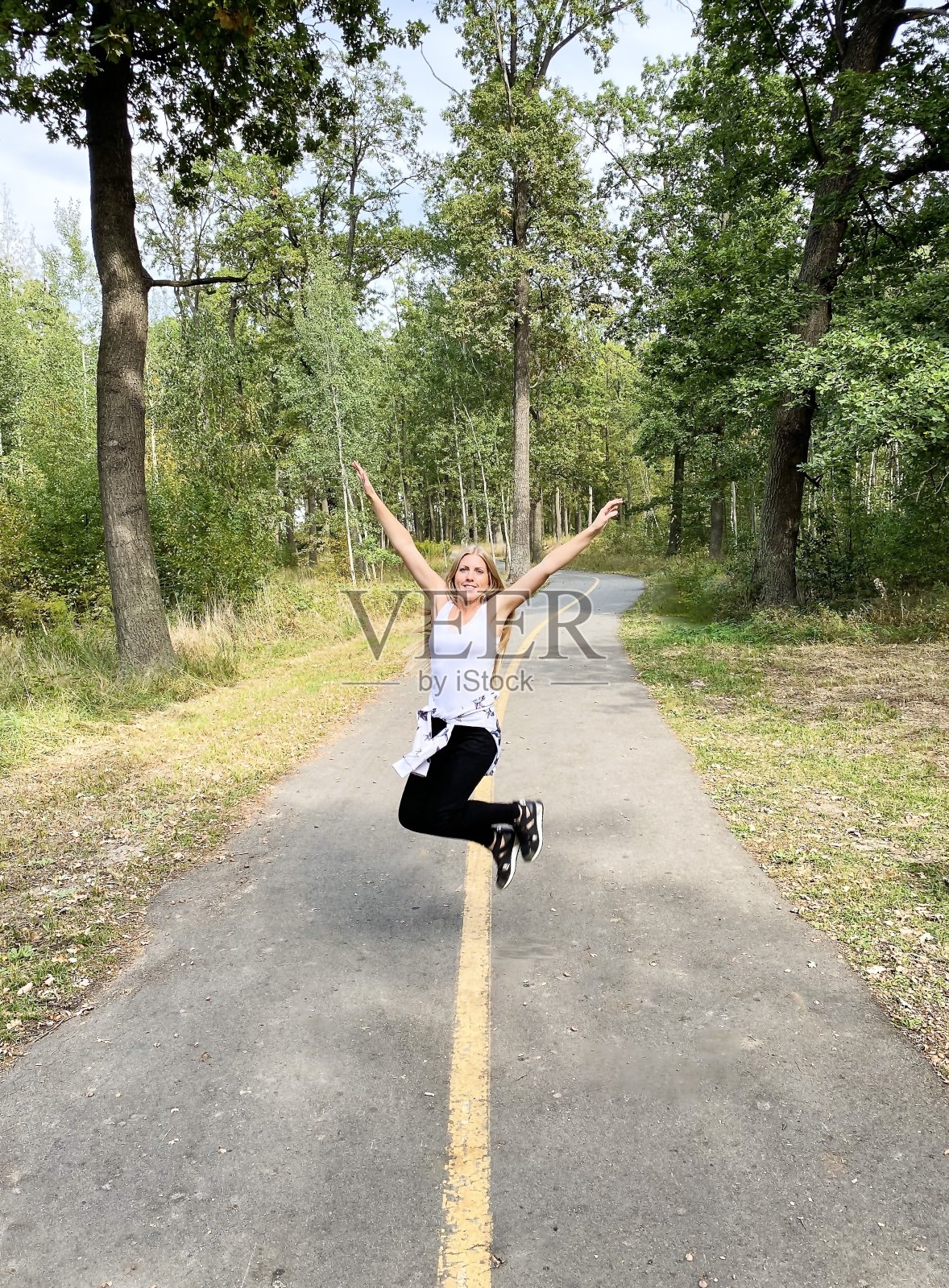 皮肤白皙的快乐女人/女孩，长头发在路上蹦蹦跳跳。自由空间。照片摄影图片