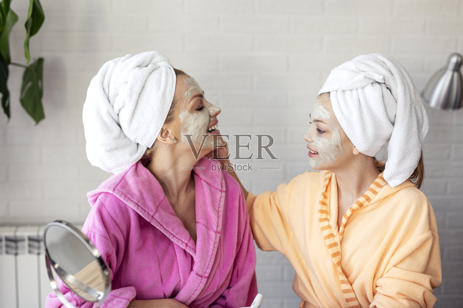 母亲和女儿将天然麝香涂抹在脸上以改善皮肤，头部用毛巾照片摄影图片