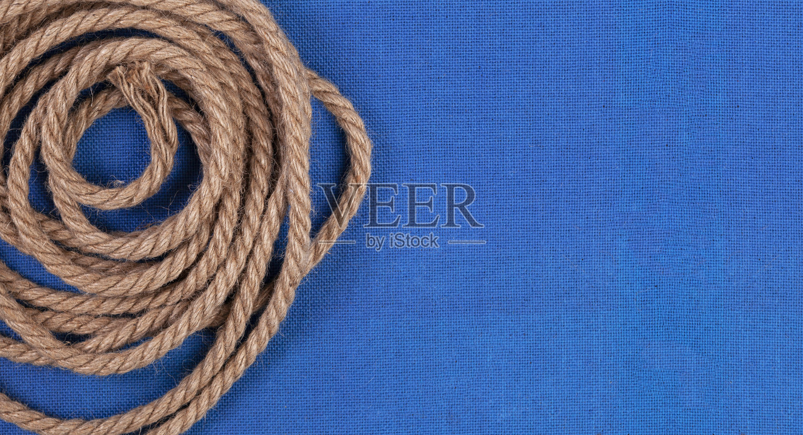 在蓝色帆布背景上扭曲的绳子照片摄影图片