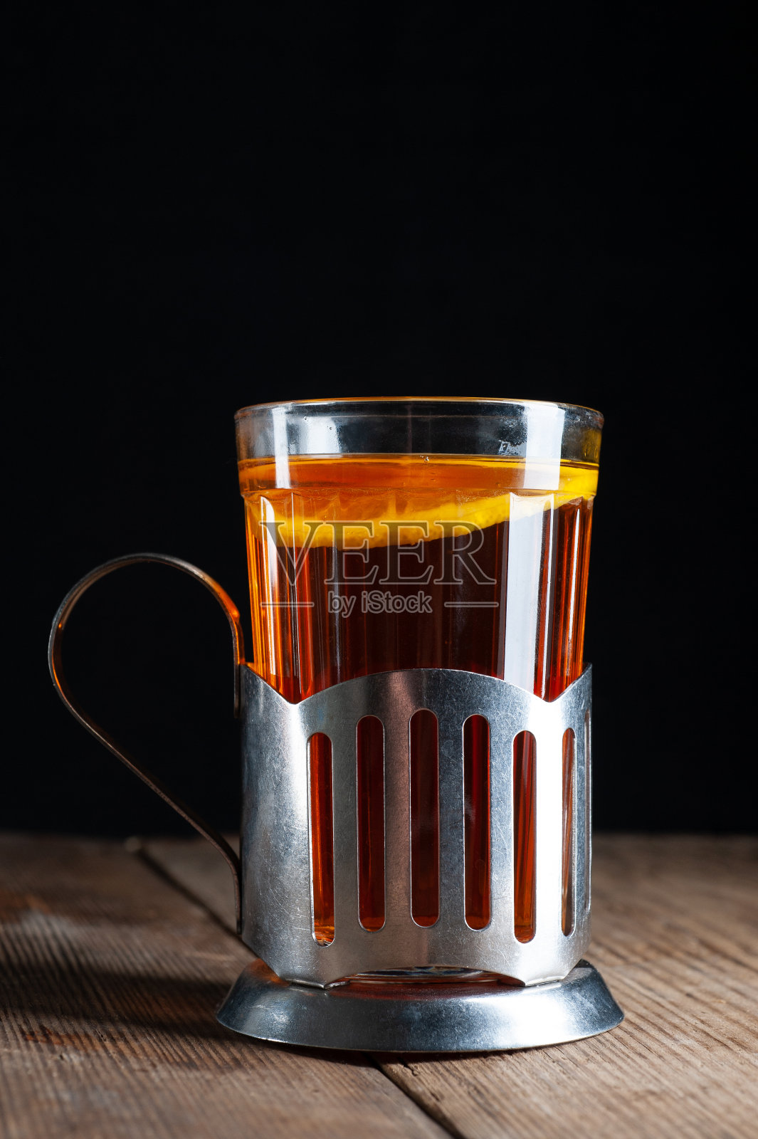 一杯柠檬茶，杯架在黑色的木制背景上照片摄影图片