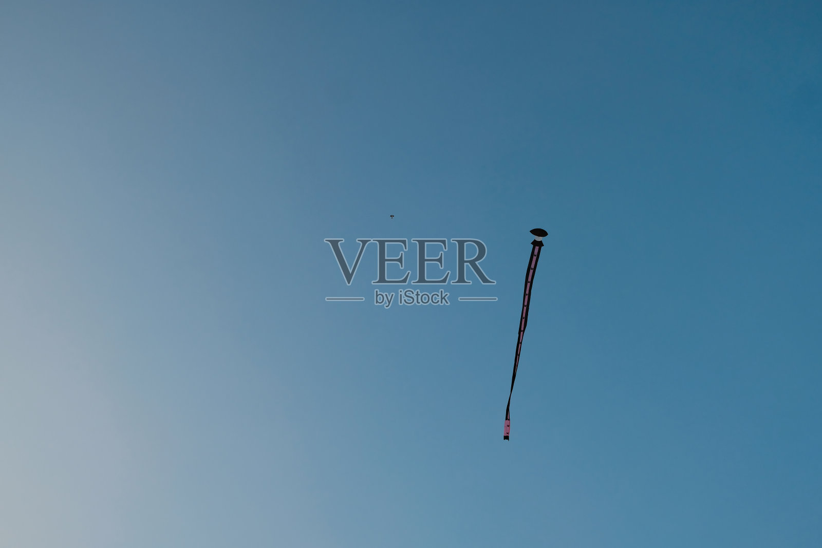 以蓝天为背景的长风筝照片摄影图片