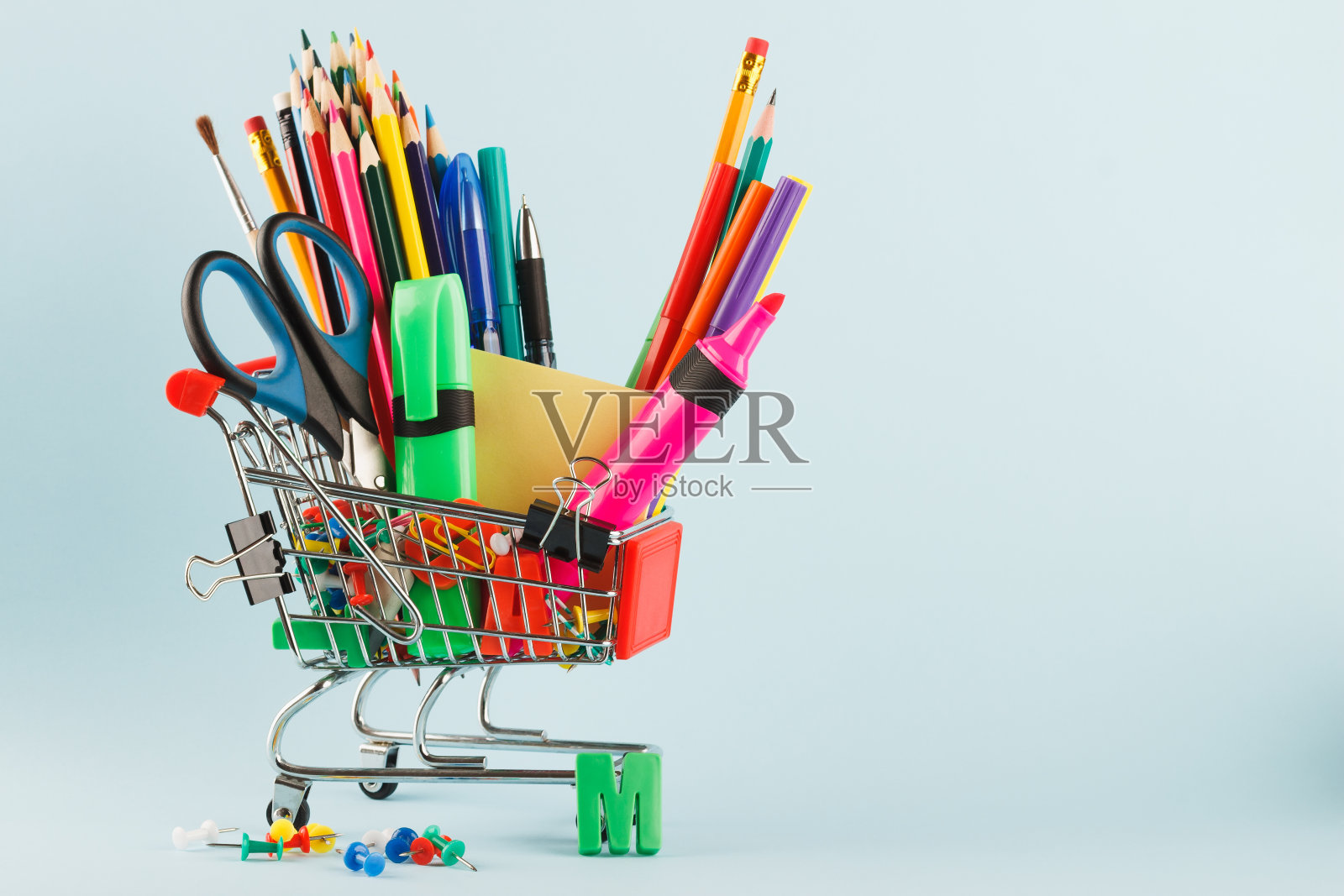 购物车用不同的文具，浅蓝色的背景照片摄影图片