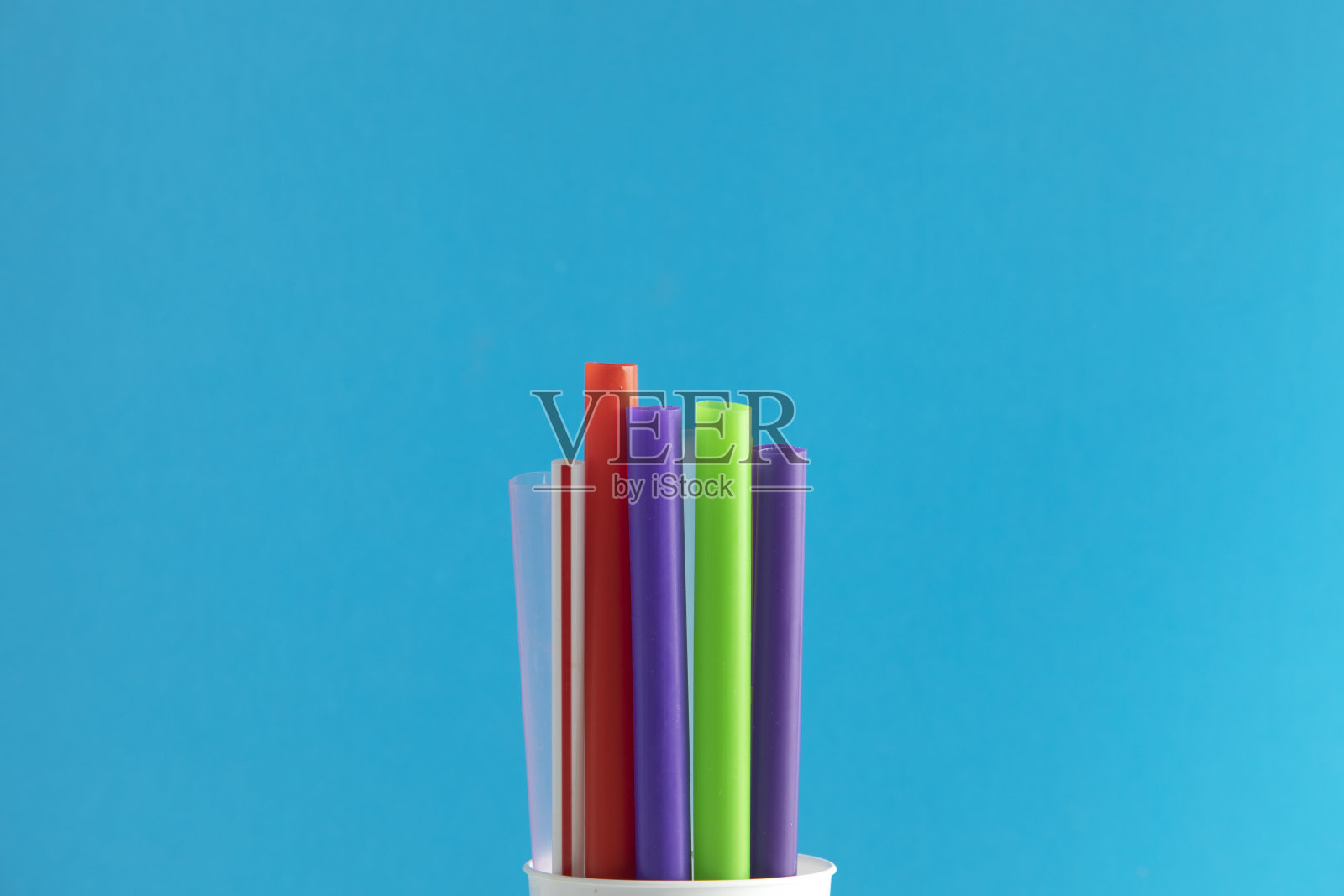 一束彩色的塑料吸管孤立在蓝色背景近距离。一次性塑料吸管末端。禁止使用一次性塑料照片摄影图片