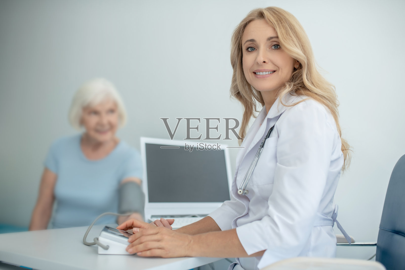 金发的年轻医生正在向一位老年病人咨询照片摄影图片