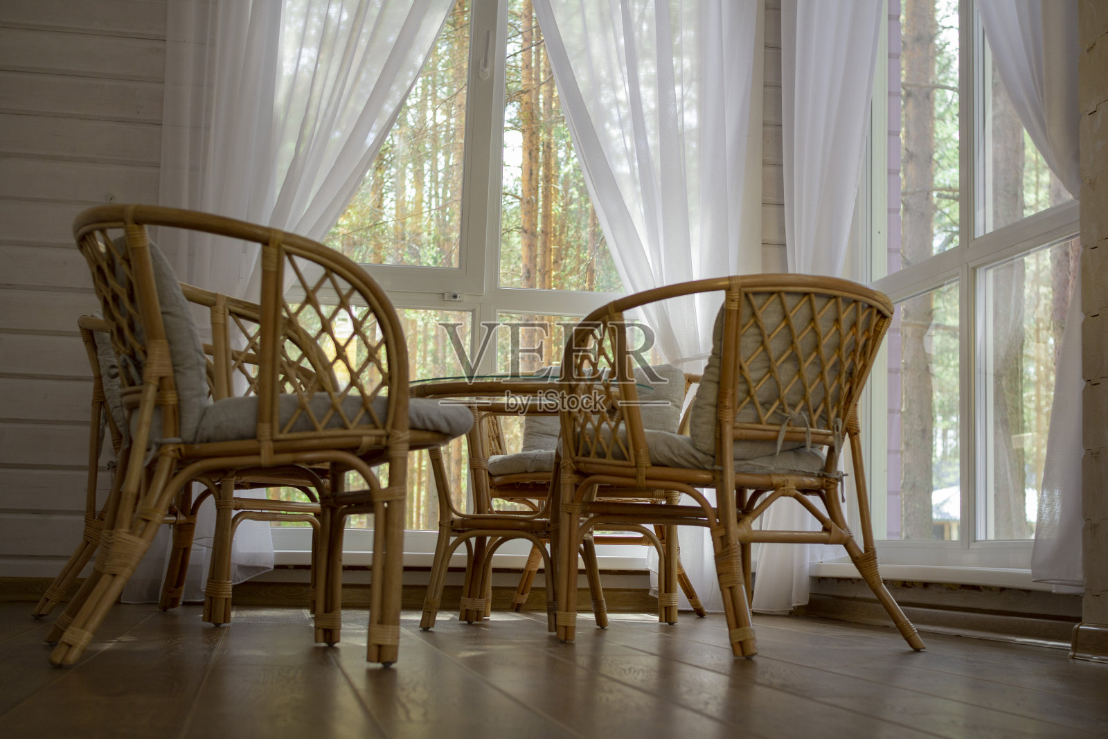 夏日门廊上的藤条家具。窗外是一片松林照片摄影图片
