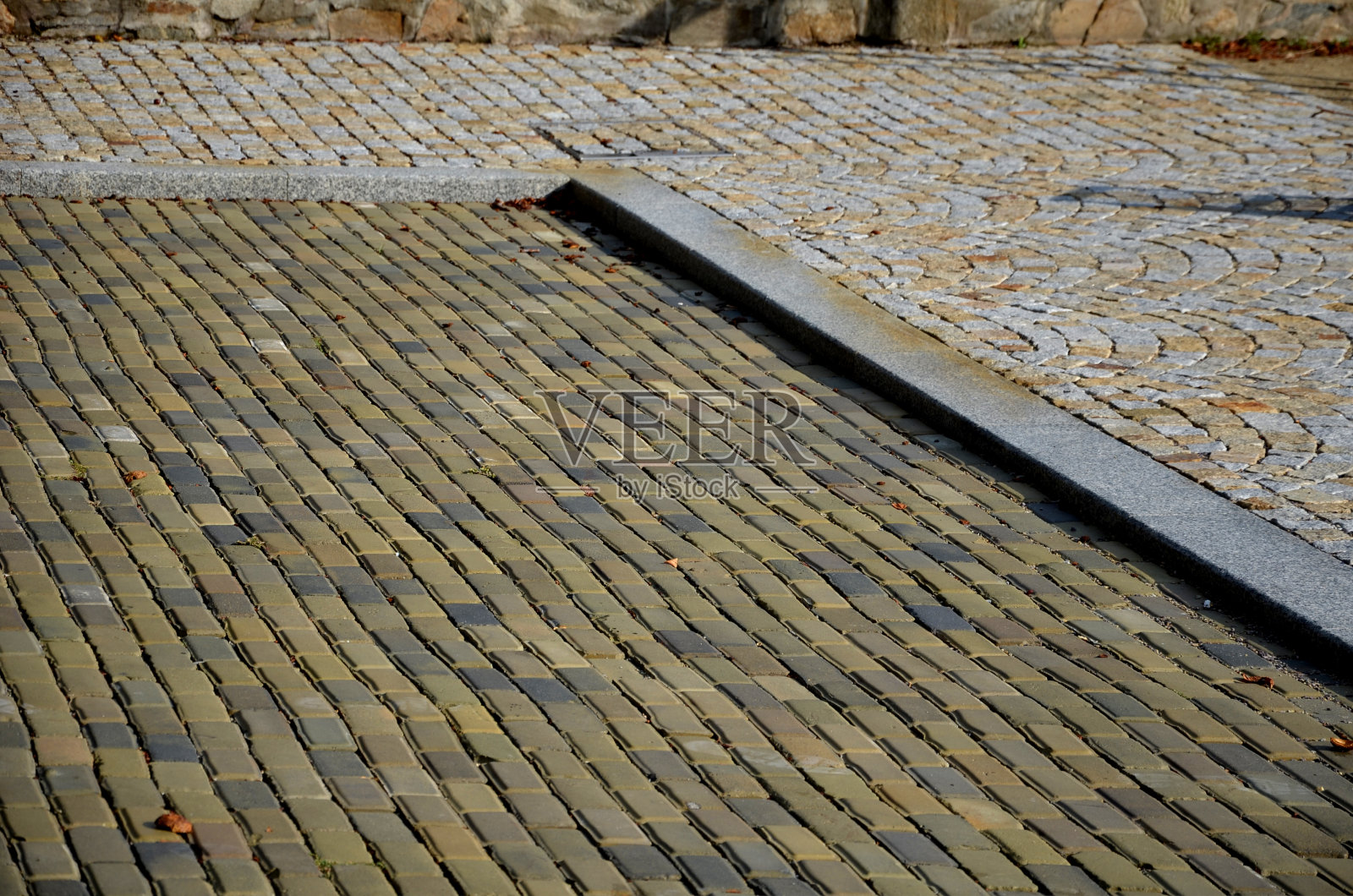 用灰色到黄色粘土制成的砖瓦，类似于互锁混凝土的旧型铺路。附件是由灰色涂漆金属铸铁制成的弯曲圆柱形状的旧系缆柱照片摄影图片