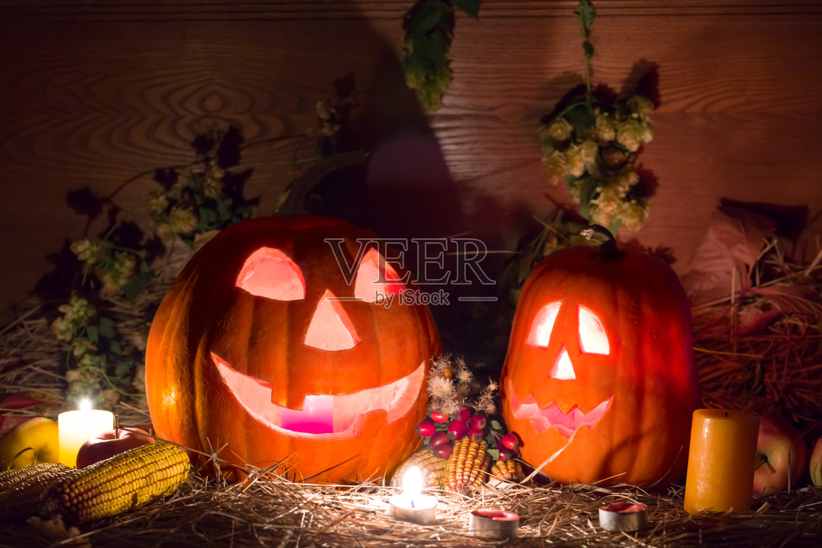 一对南瓜灯和蜡烛放在桌子上，万圣节神秘的夜晚景象照片摄影图片