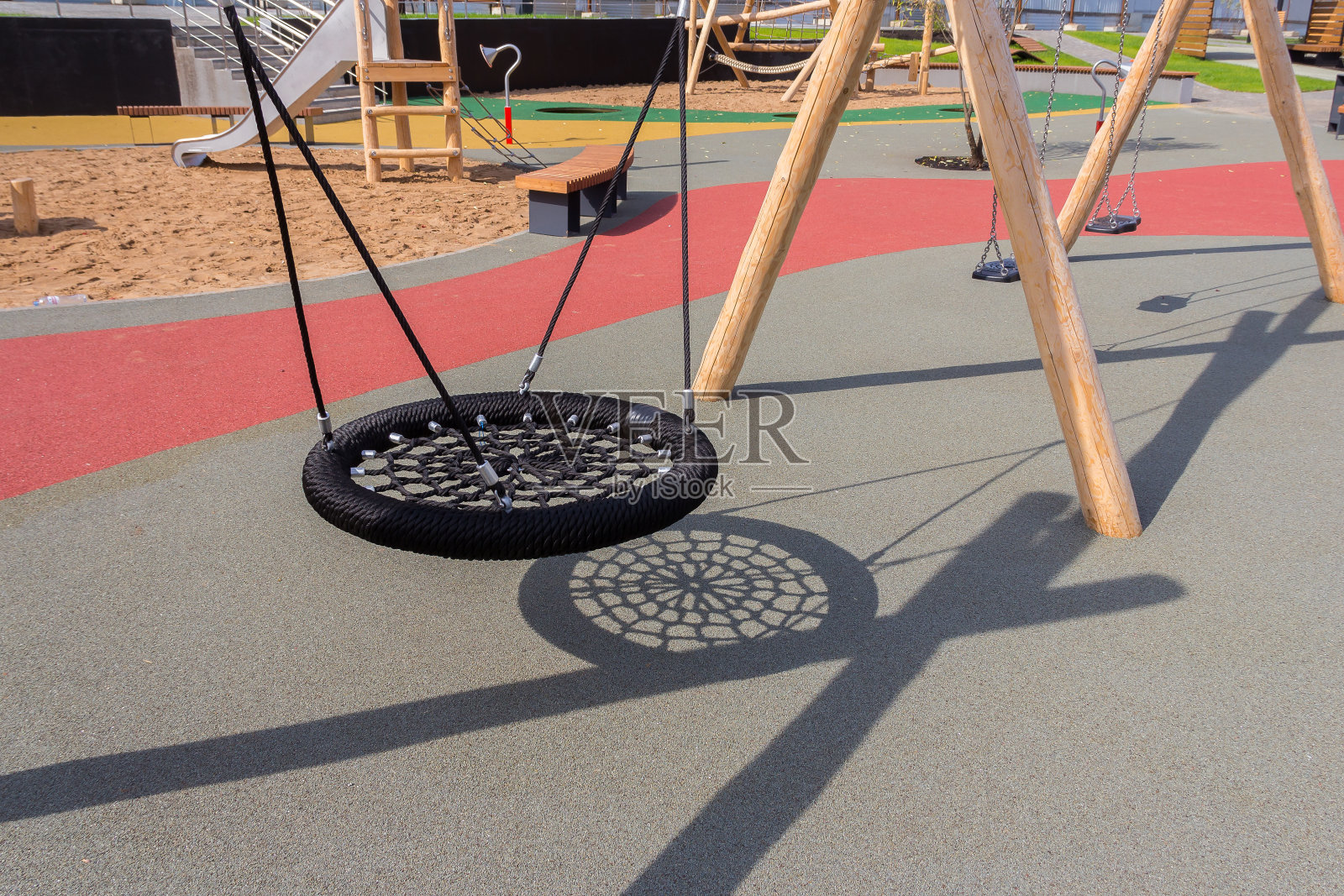 夏天在操场上荡秋千。儿童用绳子做的秋千。院子里的儿童娱乐设备。儿童游乐场有人造的软覆盖物。照片摄影图片