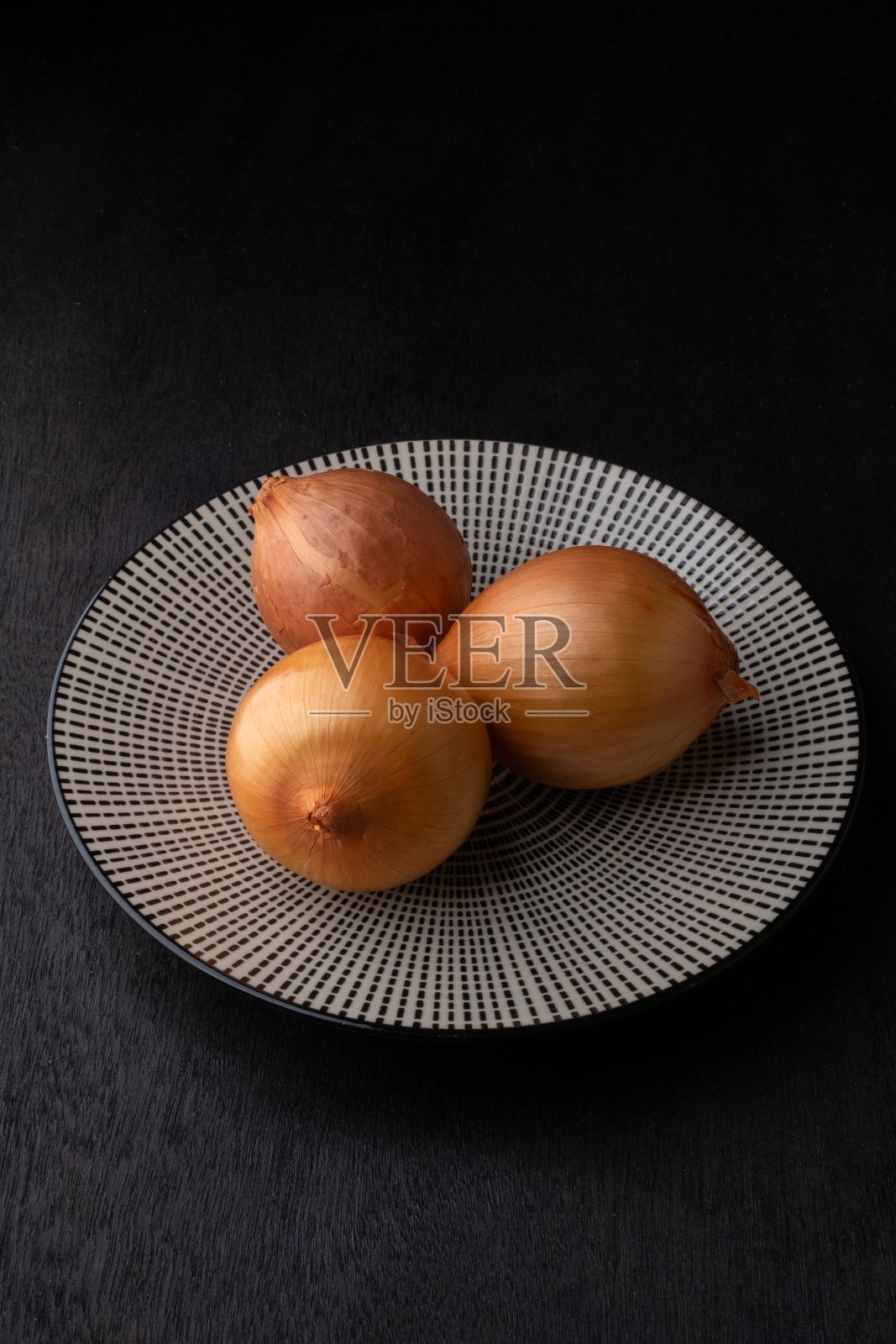 深色木色背景的盘子上放有机洋葱照片摄影图片