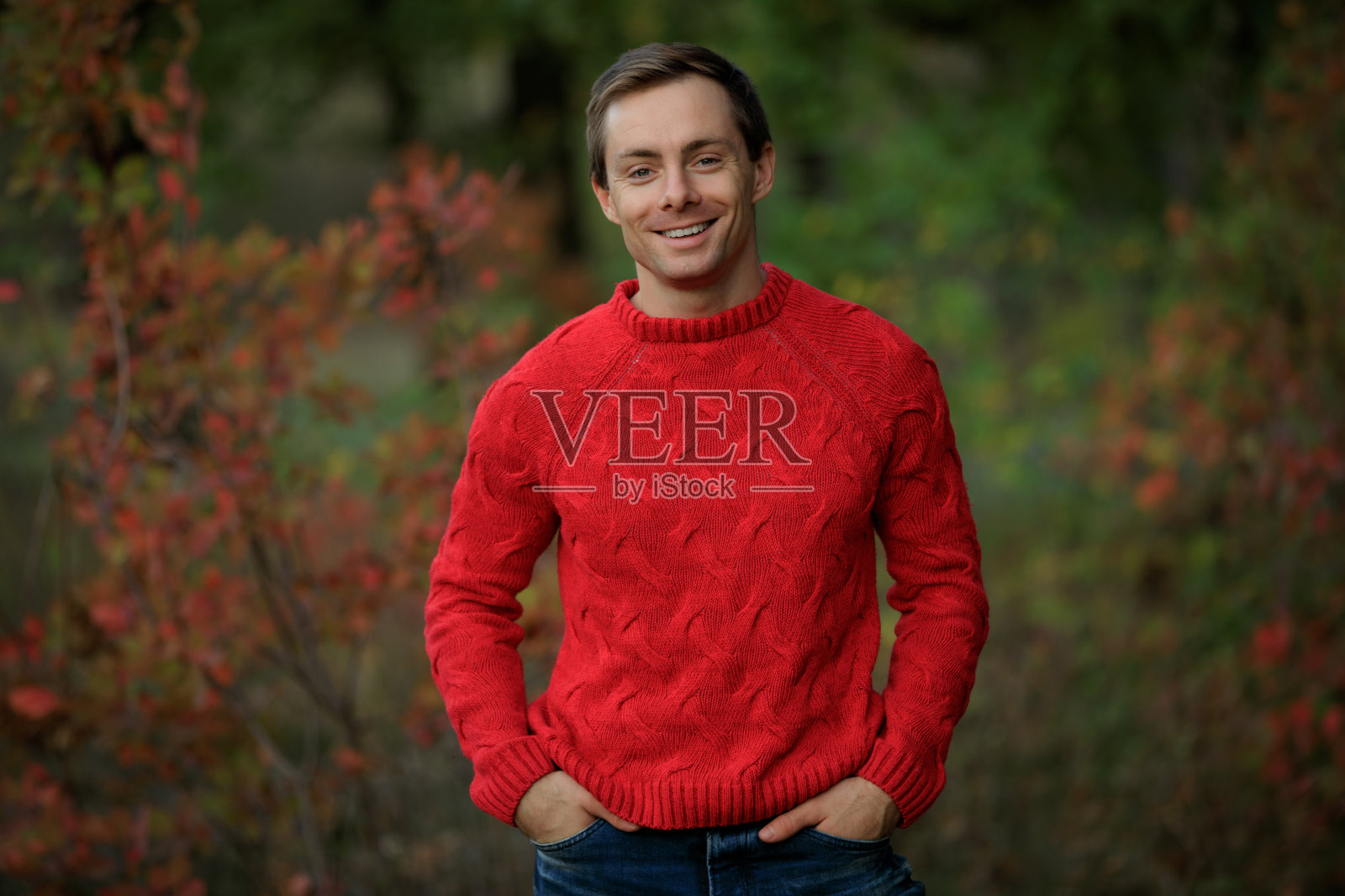 微笑的英俊男子在红毛衣照片摄影图片