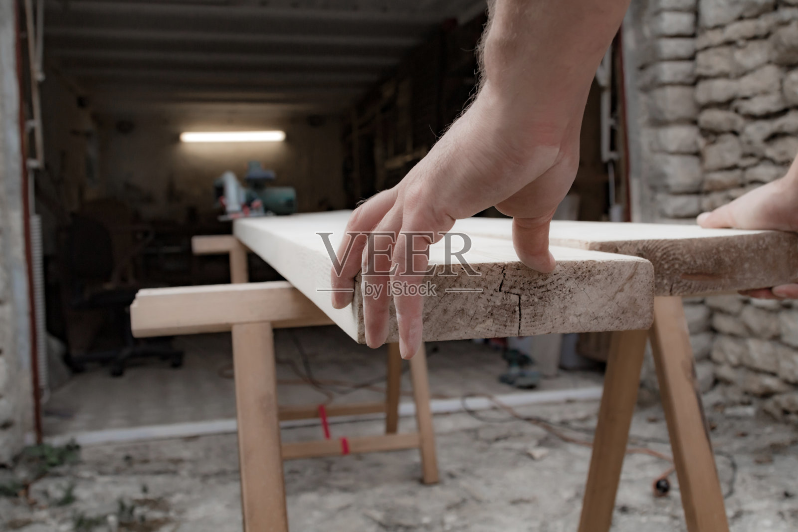 男木匠在车库里处理木材材料。照片摄影图片