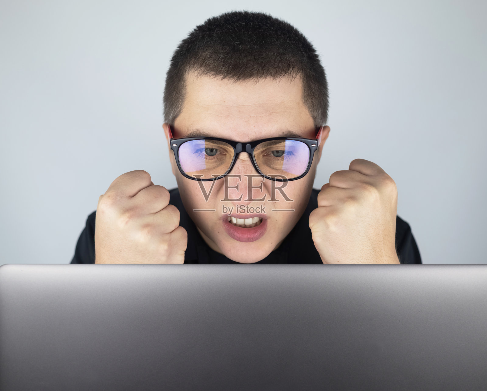 这个人看着笔记本电脑，对他在那里看到的东西感到生气和恼火。对你在网上看到的东西表达情绪和做出反应。令人震惊的内容概念。照片摄影图片