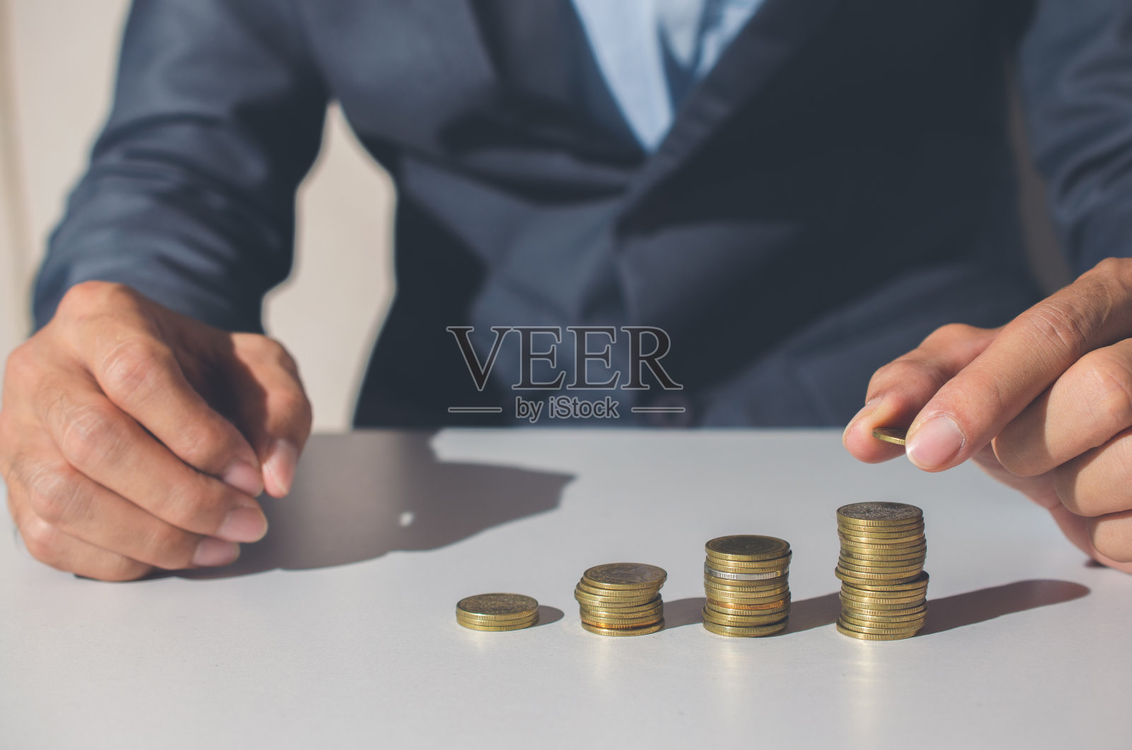 企业财务节约理念。商人把硬币叠成一排成长起来为金钱投资财富成功。照片摄影图片