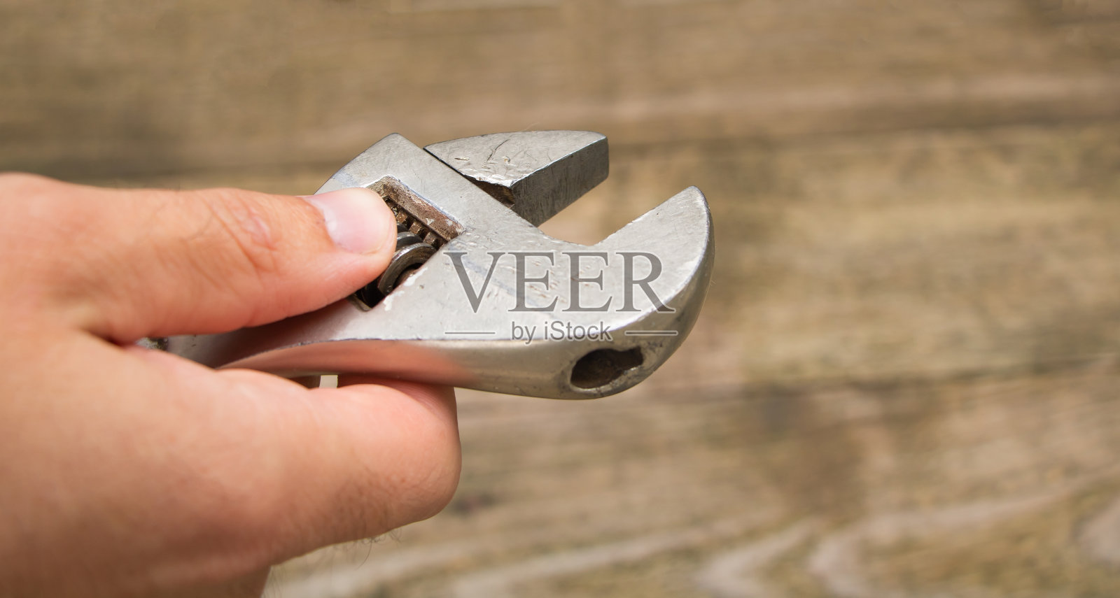 技工手里的钥匙。木制背景照片摄影图片