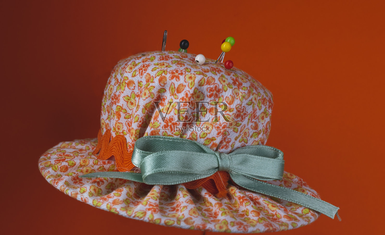 非常鲜艳的小布衬里帽，用于刺多色缝针，橙色背景照片摄影图片