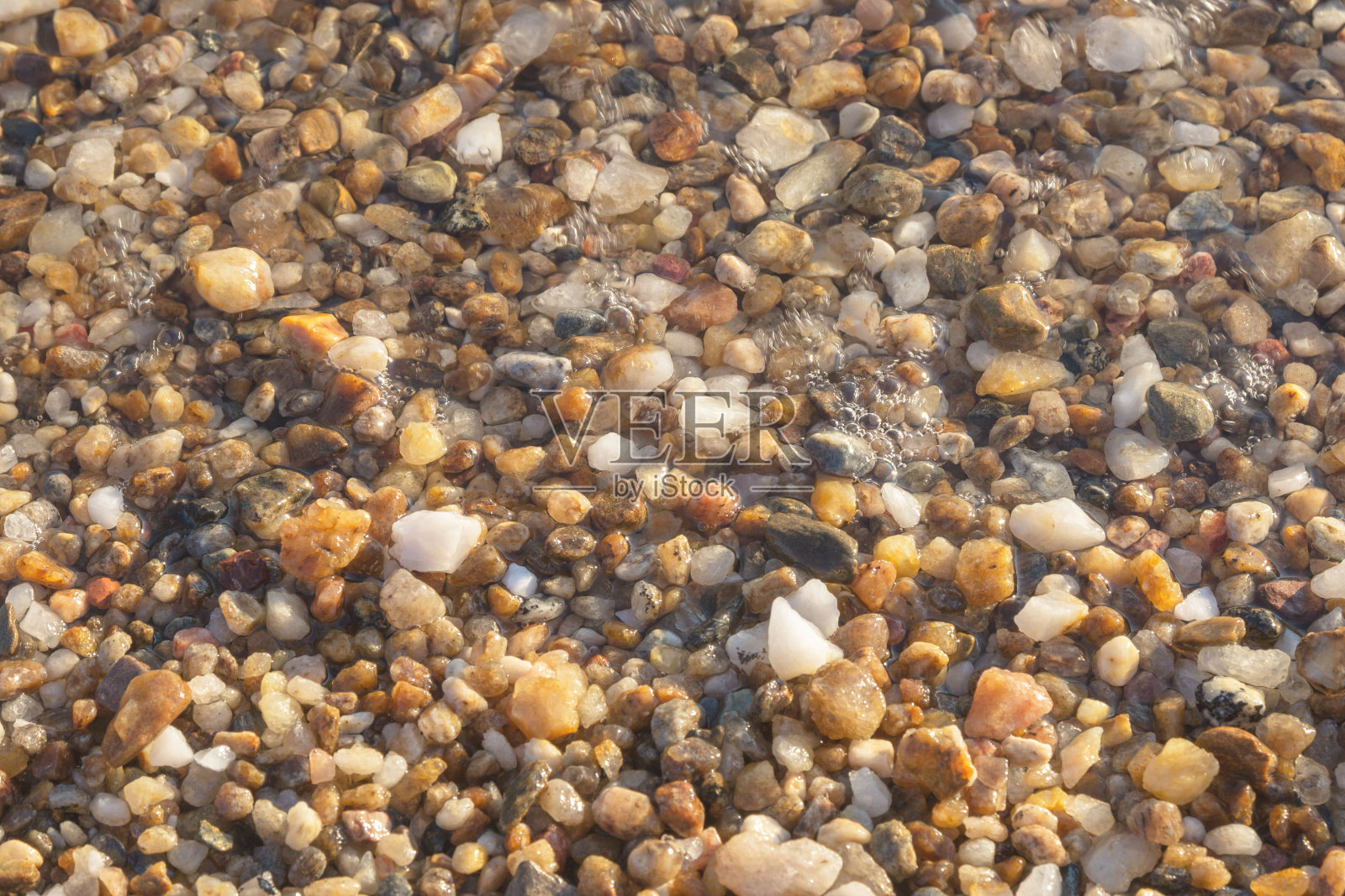 海水冲刷着棕色的小石头。石头的背景。海岸。照片摄影图片