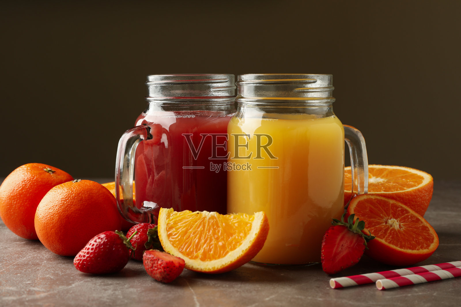 灰色背景上有草莓和橙汁的玻璃罐照片摄影图片