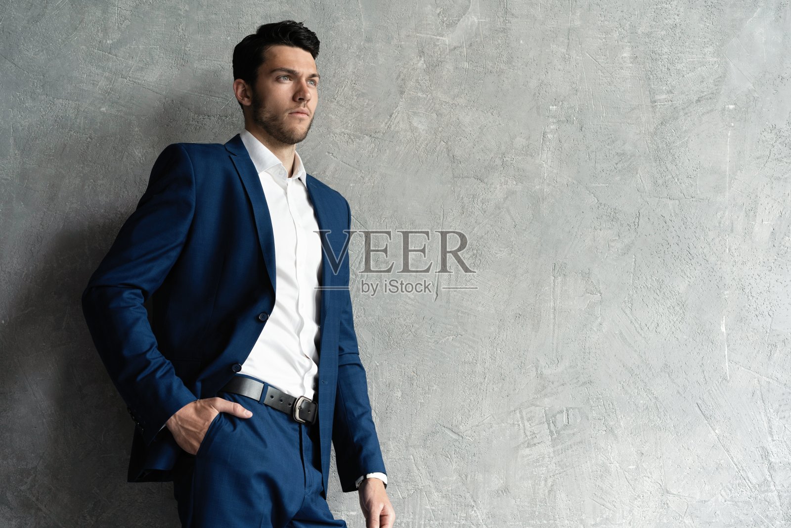 英俊的男子穿着蓝色西装孤立在灰色背景。照片摄影图片